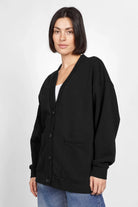 Frau trägt schwarze Relaxed Fit Sweatjacke mit Knopfleiste und aufgesetzten Taschen