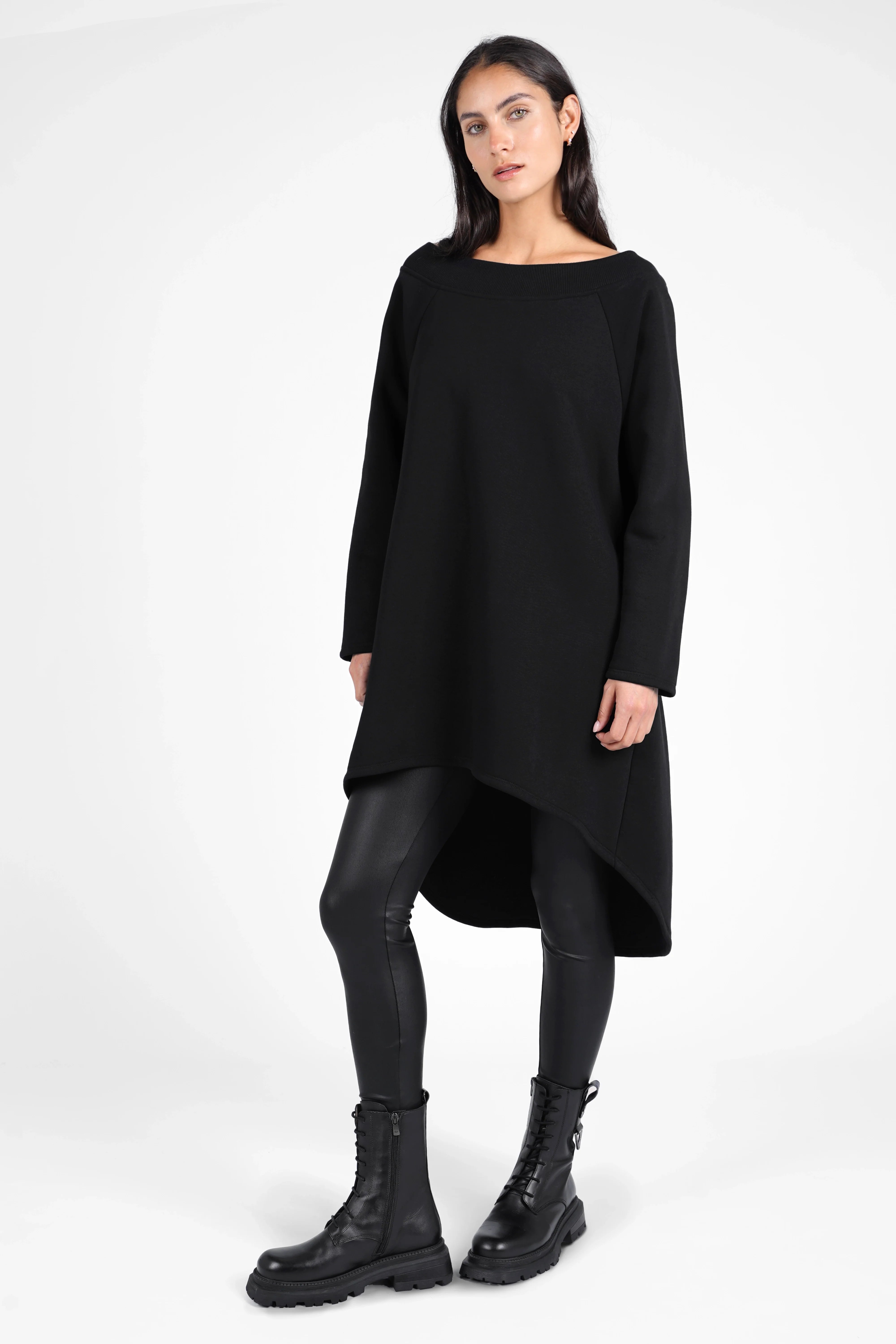 Woman wearing black CHERIN Super-Longsweater with wide boat neck and asymmetrical hem paired with black leggings and combat boots