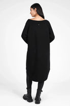 Woman wearing black CHERIN Super-Longsweater with wide boat neckline and long relaxed fit back hem.