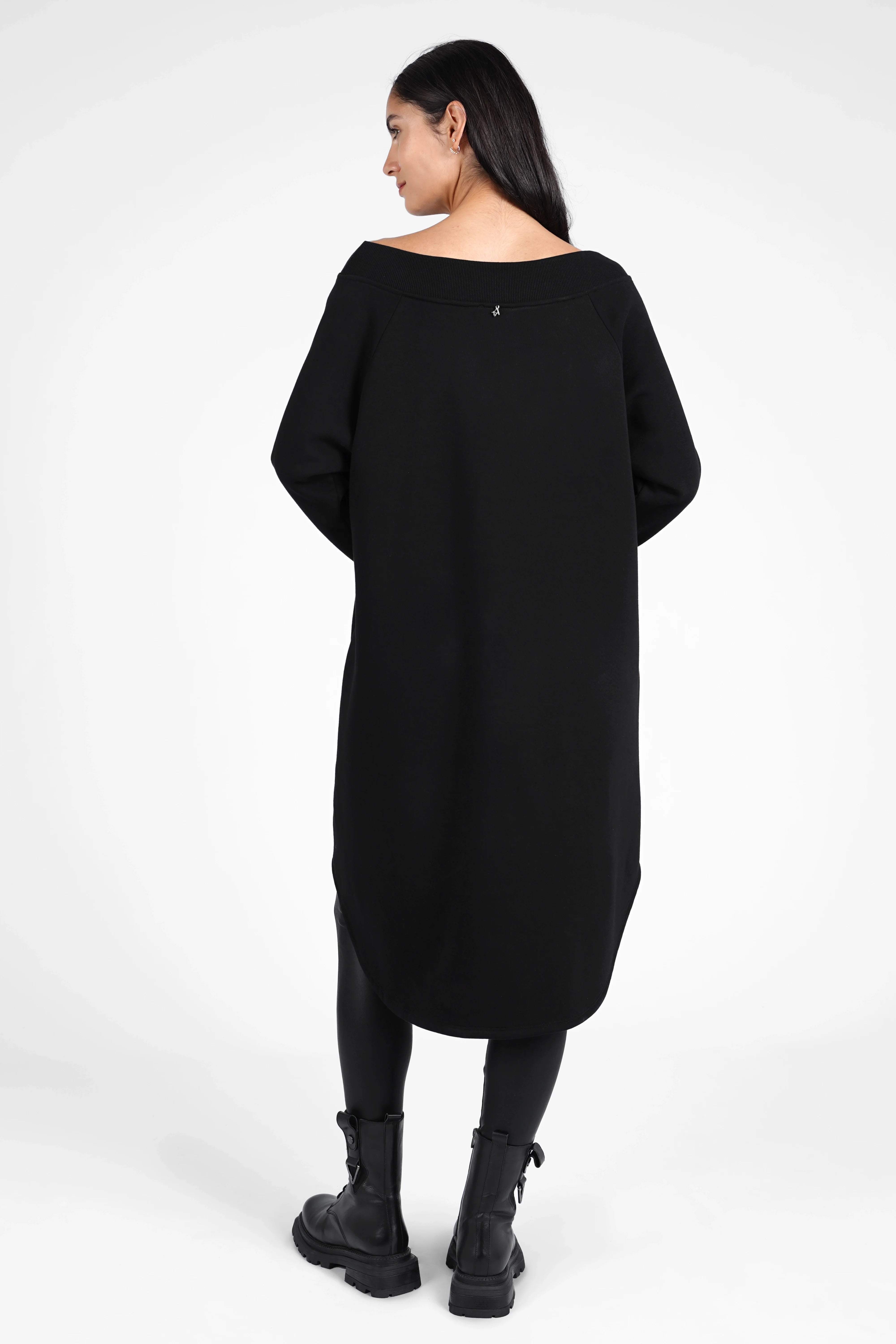 Woman wearing black CHERIN Super-Longsweater with wide boat neckline and long relaxed fit back hem.