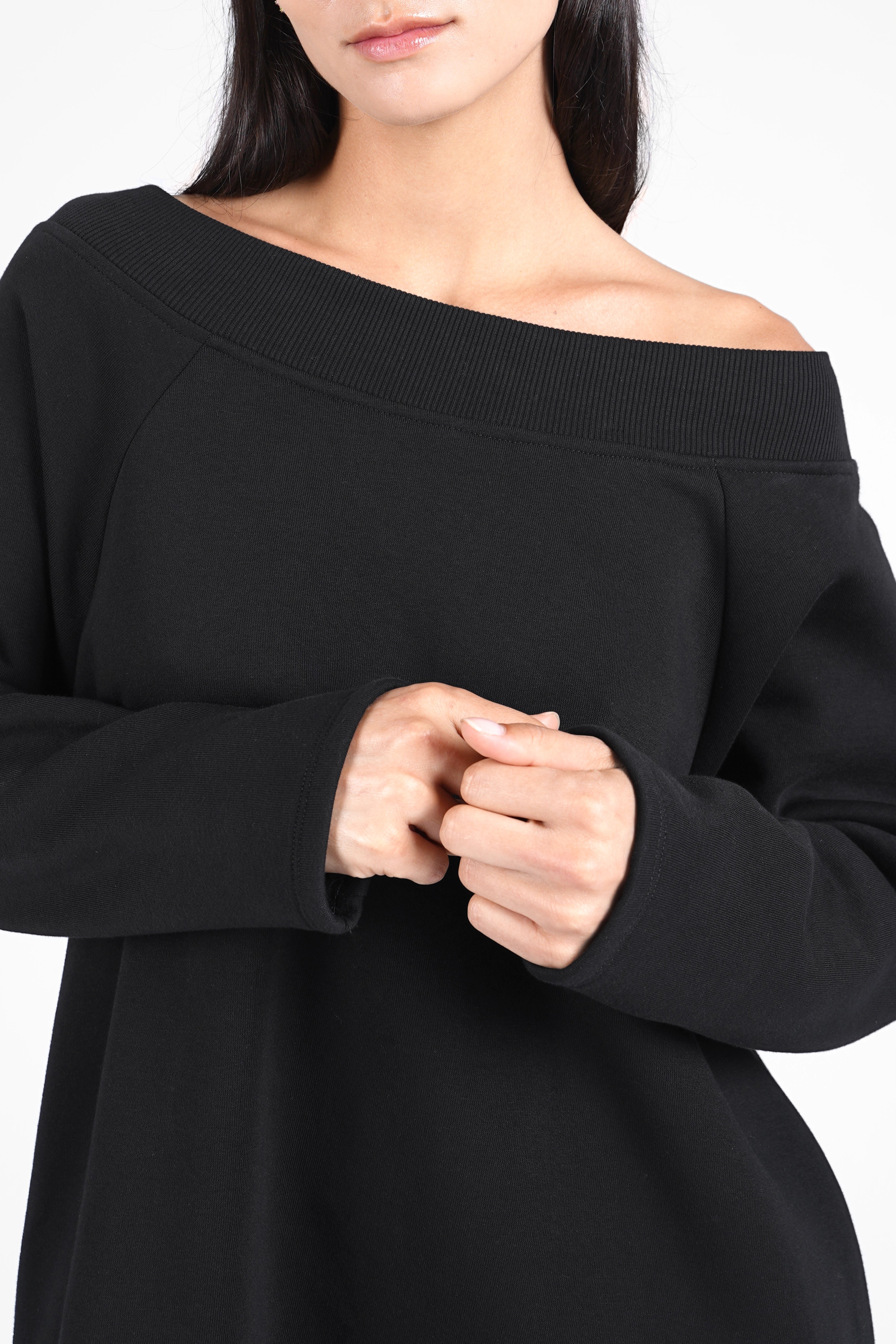 Black super-long sweater with wide boat neckline and relaxed fit on model.