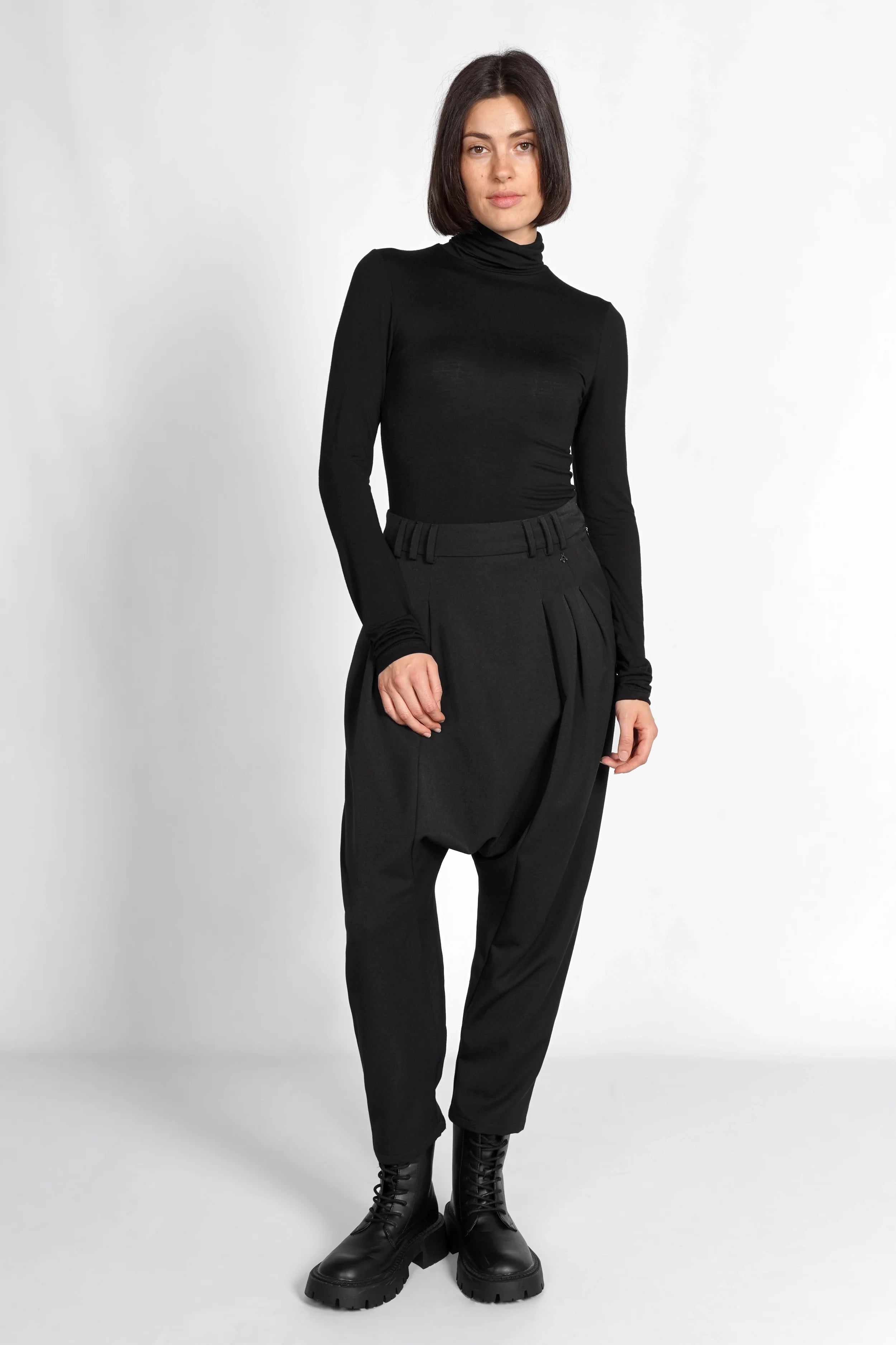 schwarze DEEP Avantgarde-Hose mit extra tiefem Schritt, Bundfalten und seitlicher Knopfschließe, entspannter Schnitt und tapered Leg