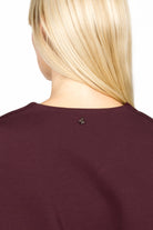 Back view of BERLEY Relaxed V-Neck Bluse in dark burgundy jersey material showing relaxed fit and minimal detailing at neckline.