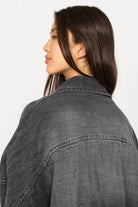 Frau trägt ANEA Oversized Hemdjacke im Denim-Look mit überschnittenen Schultern und abgerundetem Saum, Rückansicht