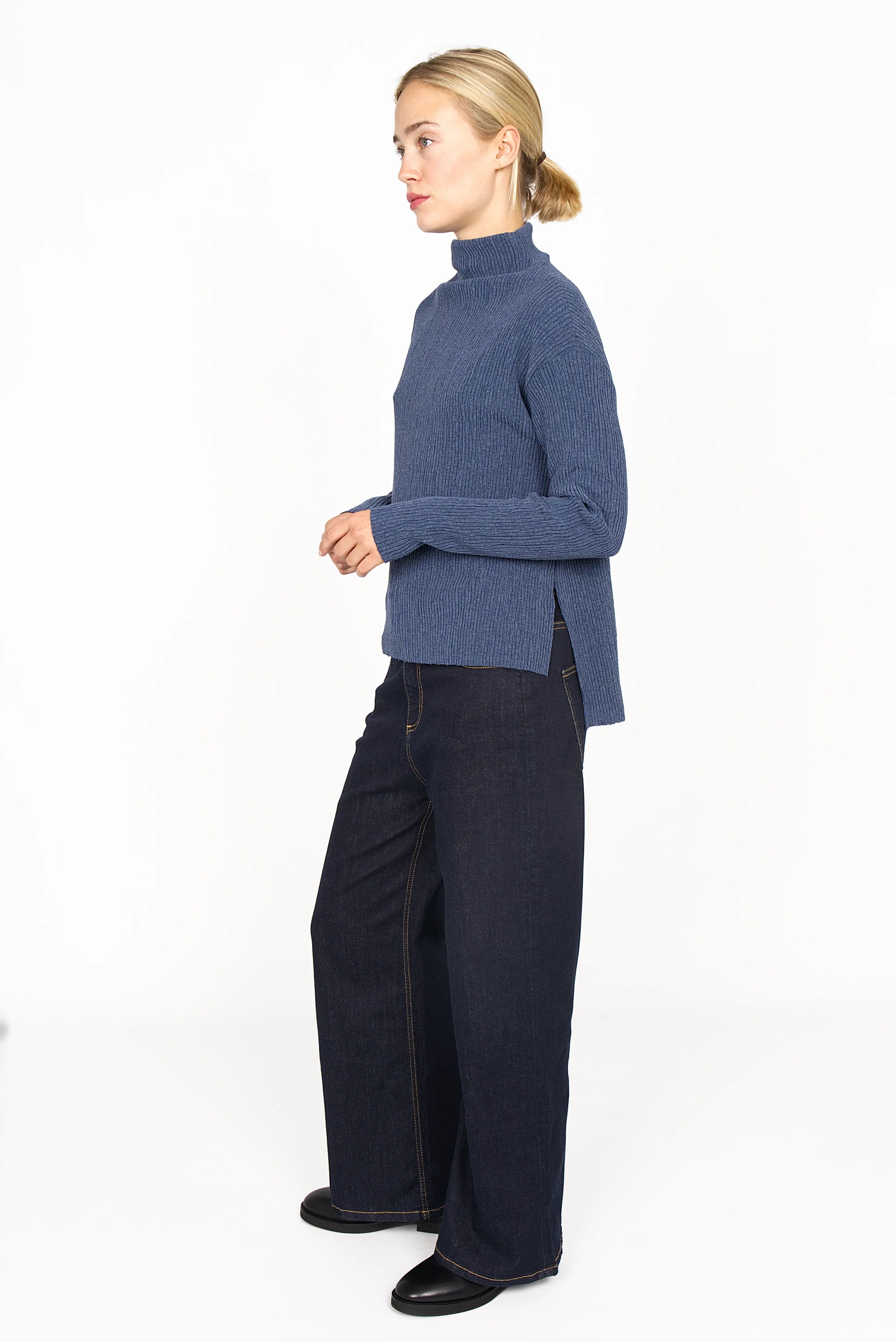NORELI Longsleeve in blue plissier crepe jersey with mock neck, side slits, and dropped shoulders worn with dark wide-leg jeans