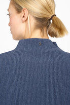 Back view of a woman wearing a blue NORELI Longsleeve with mock neck and ribbed texture.