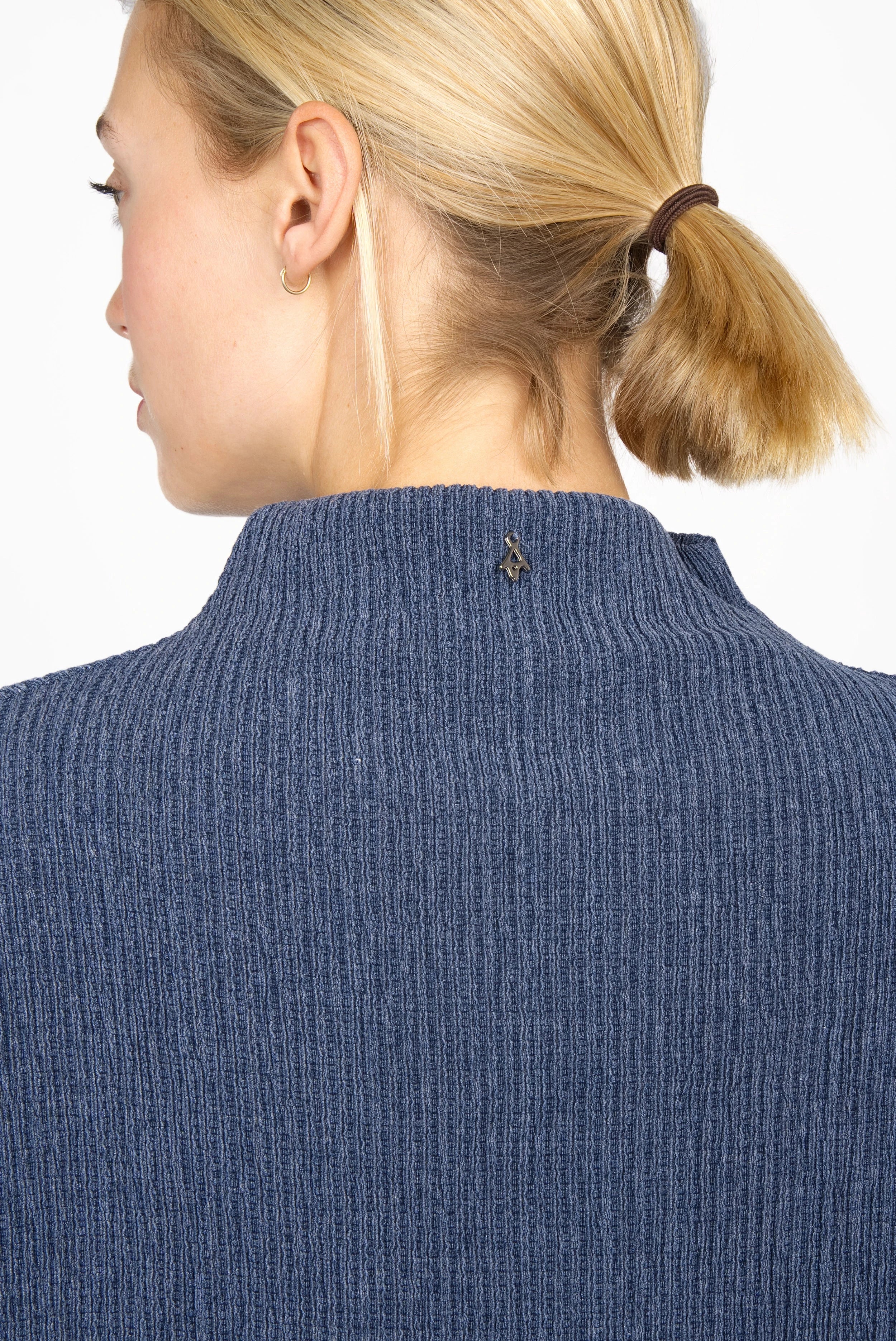 Back view of a woman wearing a blue NORELI Longsleeve with mock neck and ribbed texture.