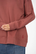 Close-up of a dusty rose EIREL oversize sweater with tonal logo embroidery and extended cuffs on the sleeves