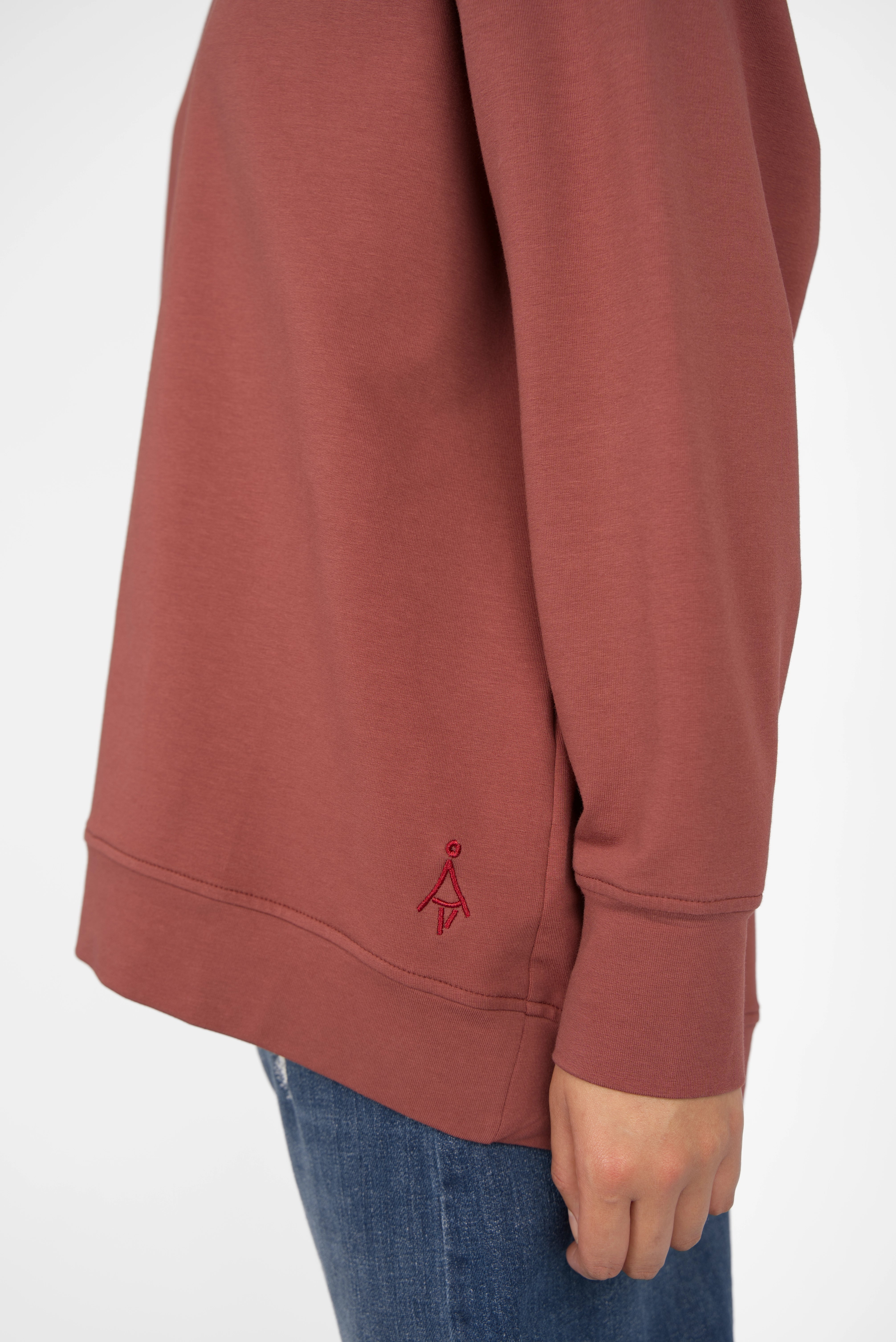 Close-up of brown EIREL oversize sweater with tonal logo embroidery and extended cuff on sleeve