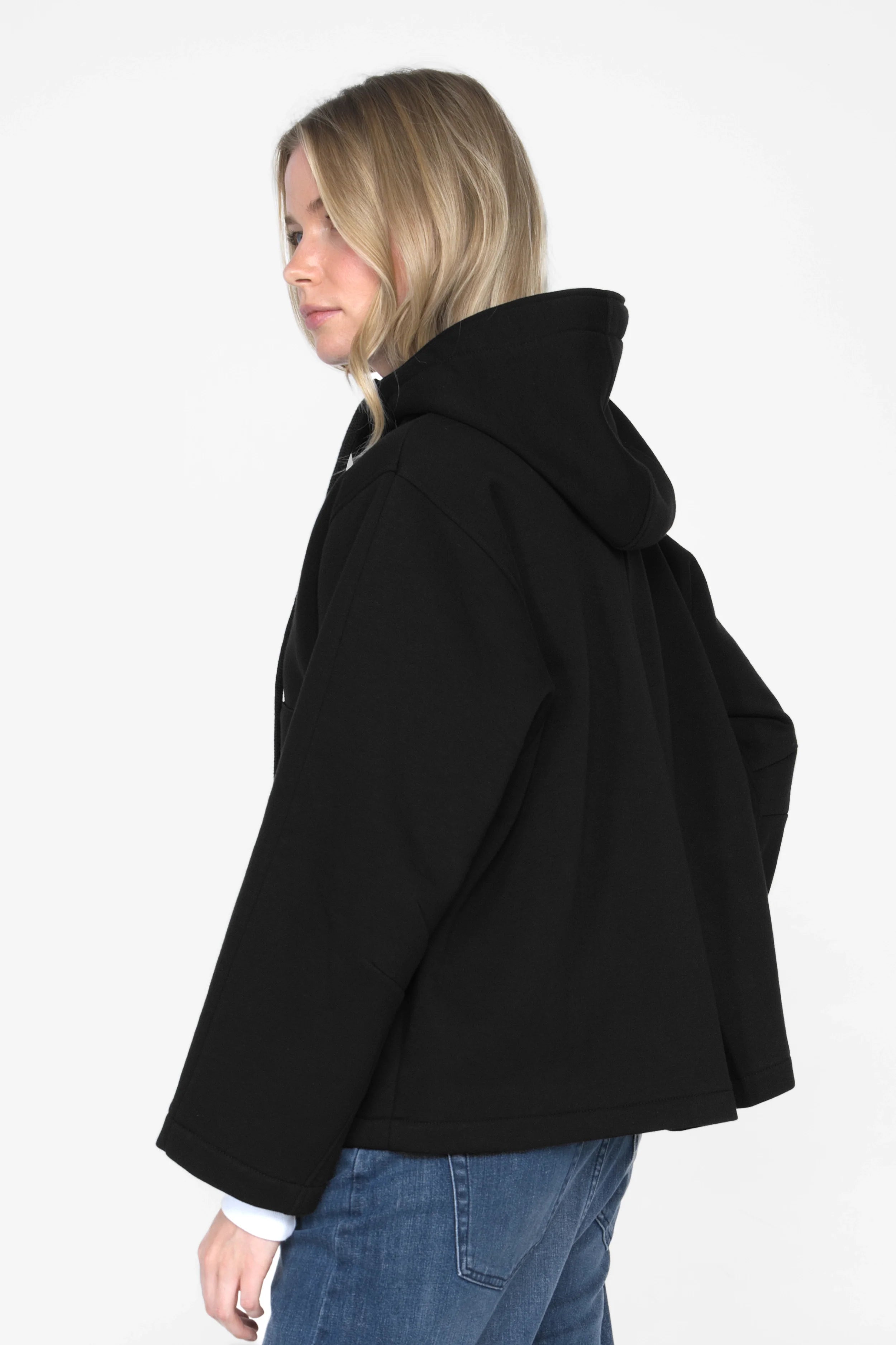 Frau trägt schwarze ELFA Sweatjacke mit Kapuze, Känguru-Taschen und entspanntem Schnitt