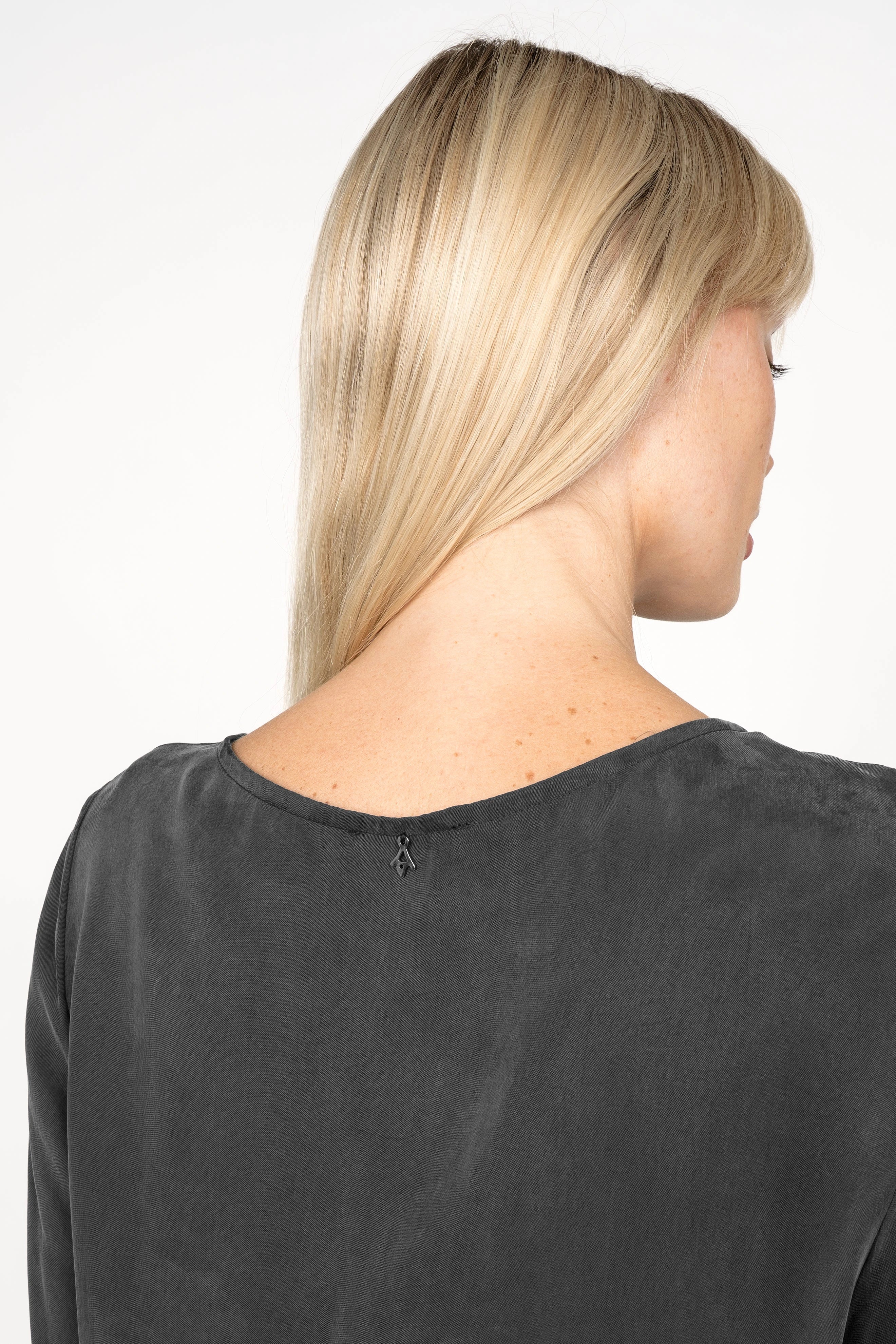 Back view of a woman wearing a black EMEDY Longbluse Tunika with a rounded neckline and soft fabric texture.