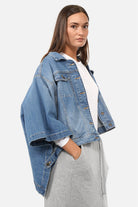 FIBI Denim Cape made in Italy with soft stretch denim, classic collar, front buttons, decorative pockets, side pockets, loose fit, and straight hem.