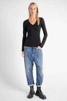 FLURRI Longsleeve black slim fit cashmere blend top with V-neck twist detail worn by model with jeans and boots