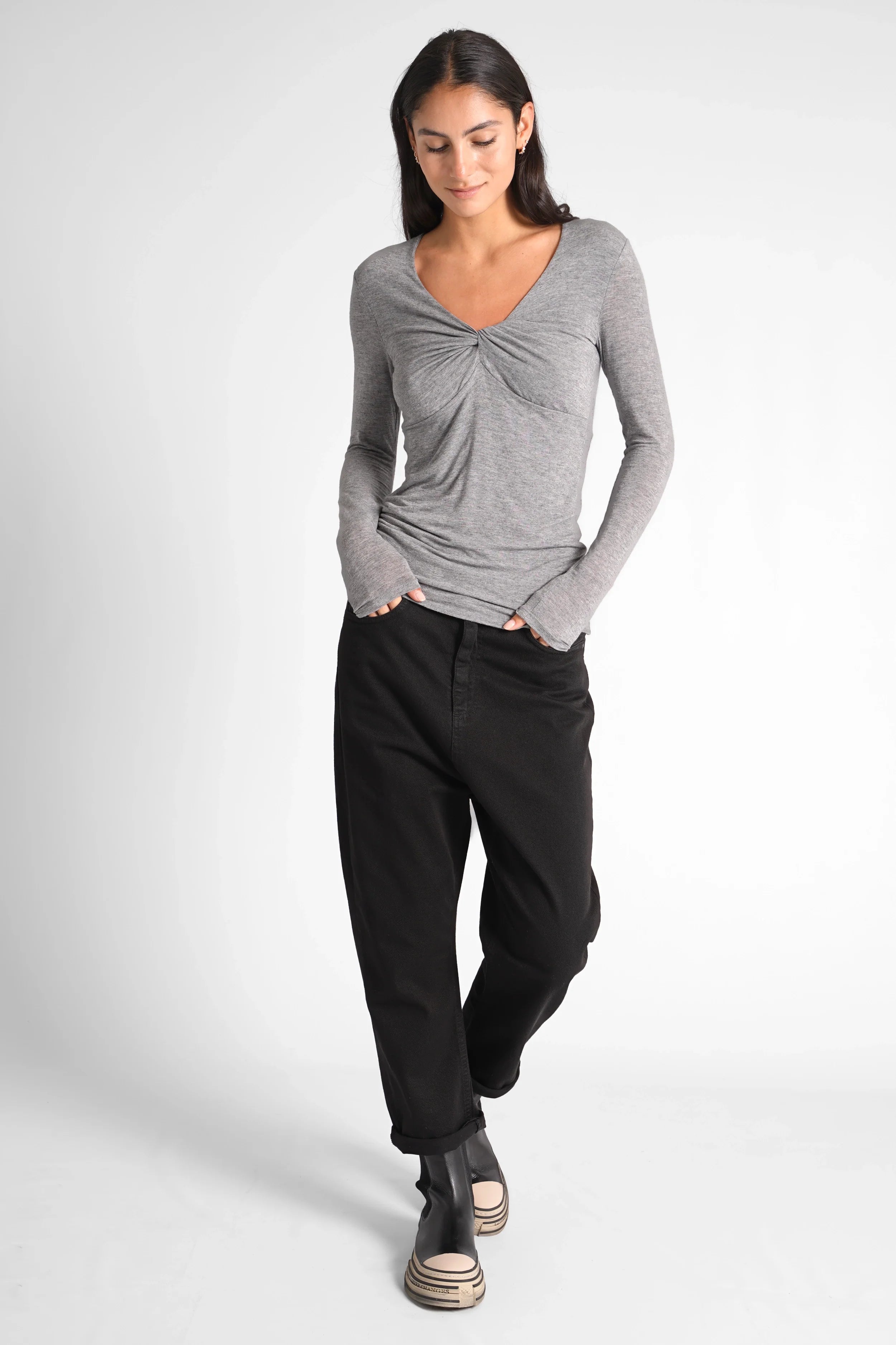 Woman wearing FLURRI Longsleeve grey slim fit V-neck top with twist detail and black pants