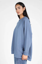 Damen trägt lässigen GRACEY.K Sweater in Blau mit A-Linie, Raglanärmeln und tonaler Logo-Stickerei