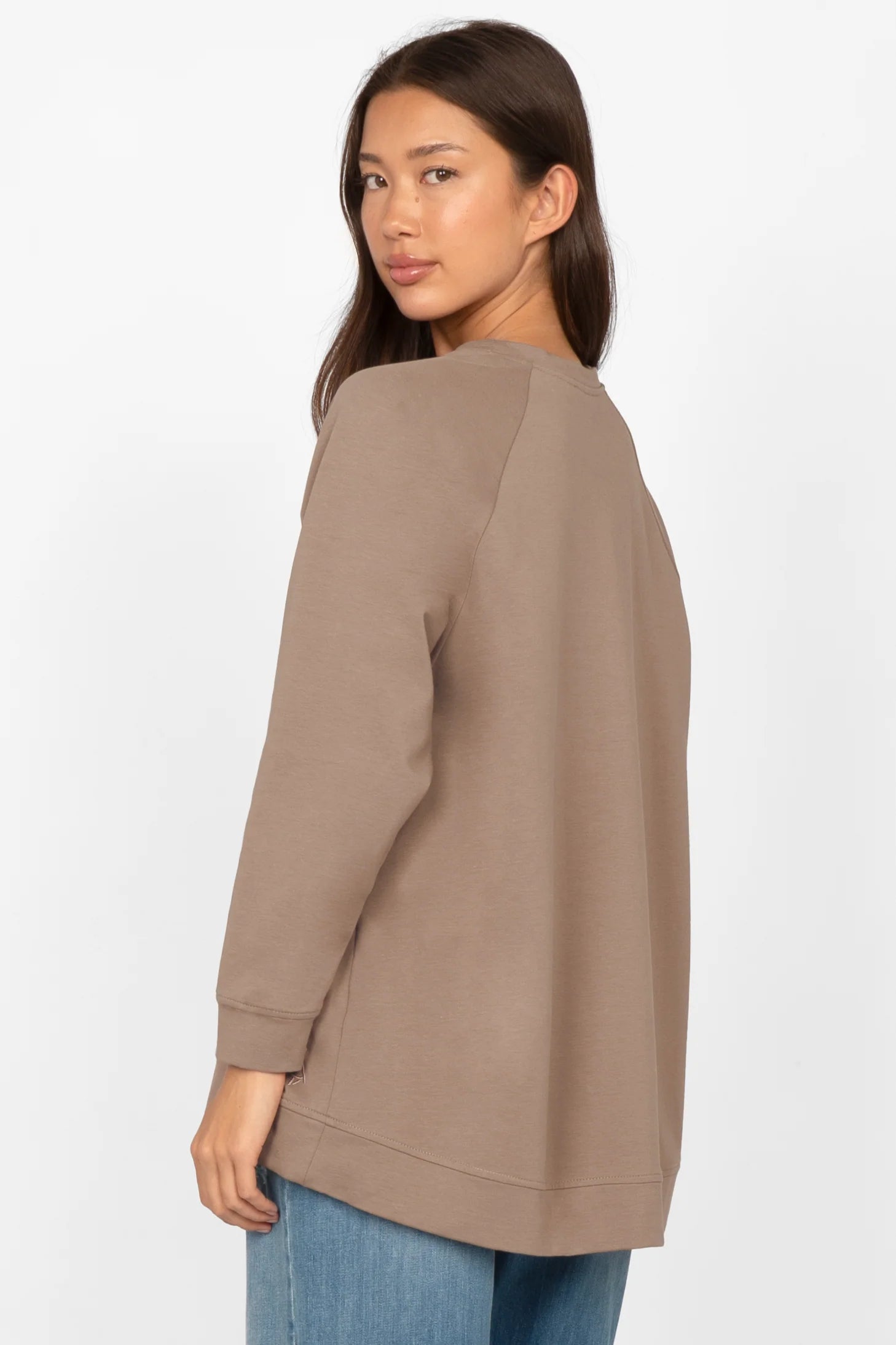 Woman wearing taupe GRACEY.K Sweater with A-line and longer back hem, paired with blue jeans