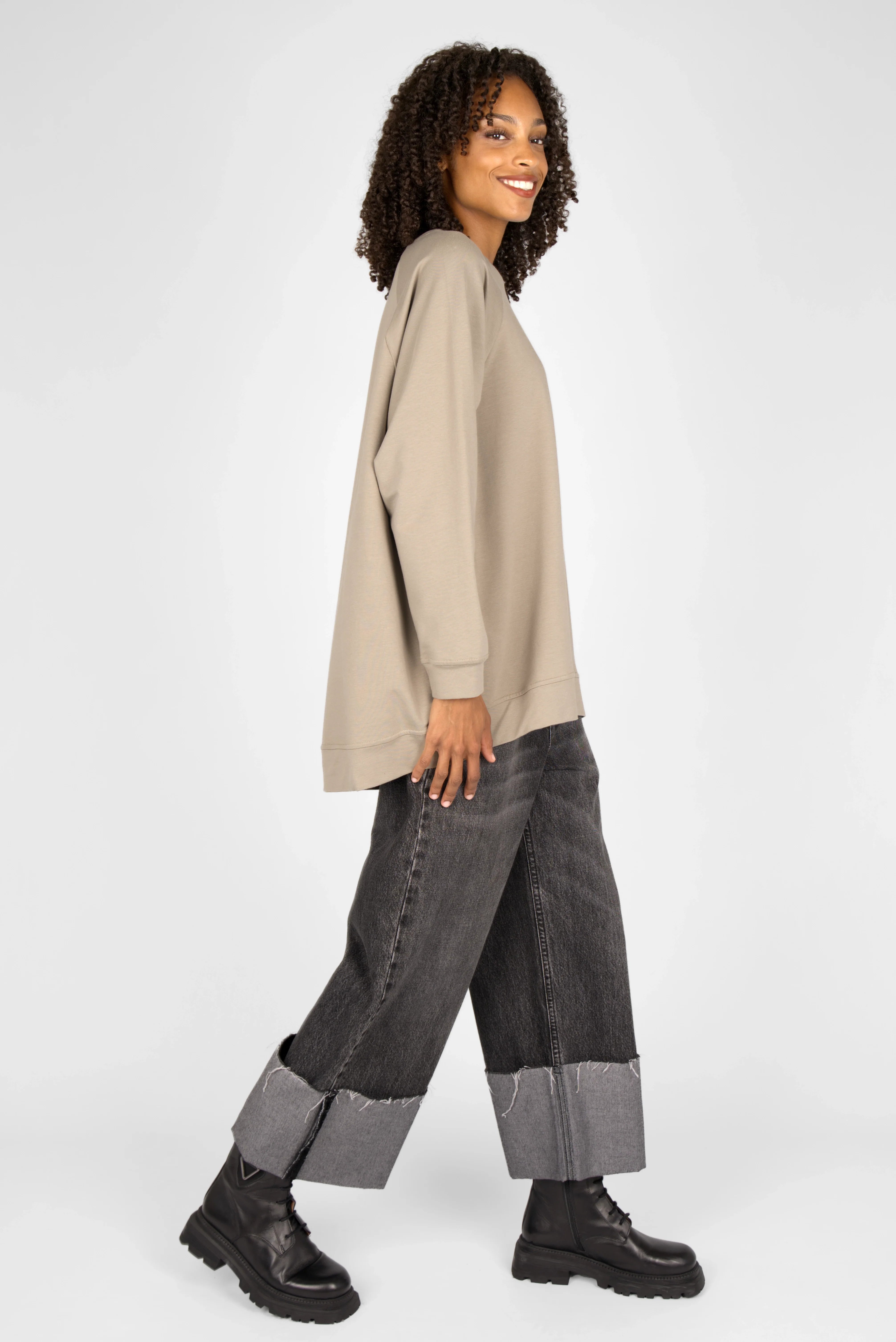 Woman wearing beige oversized GRACEY.K Sweater with A-line and rounded hem paired with cuffed wide-leg jeans and black boots