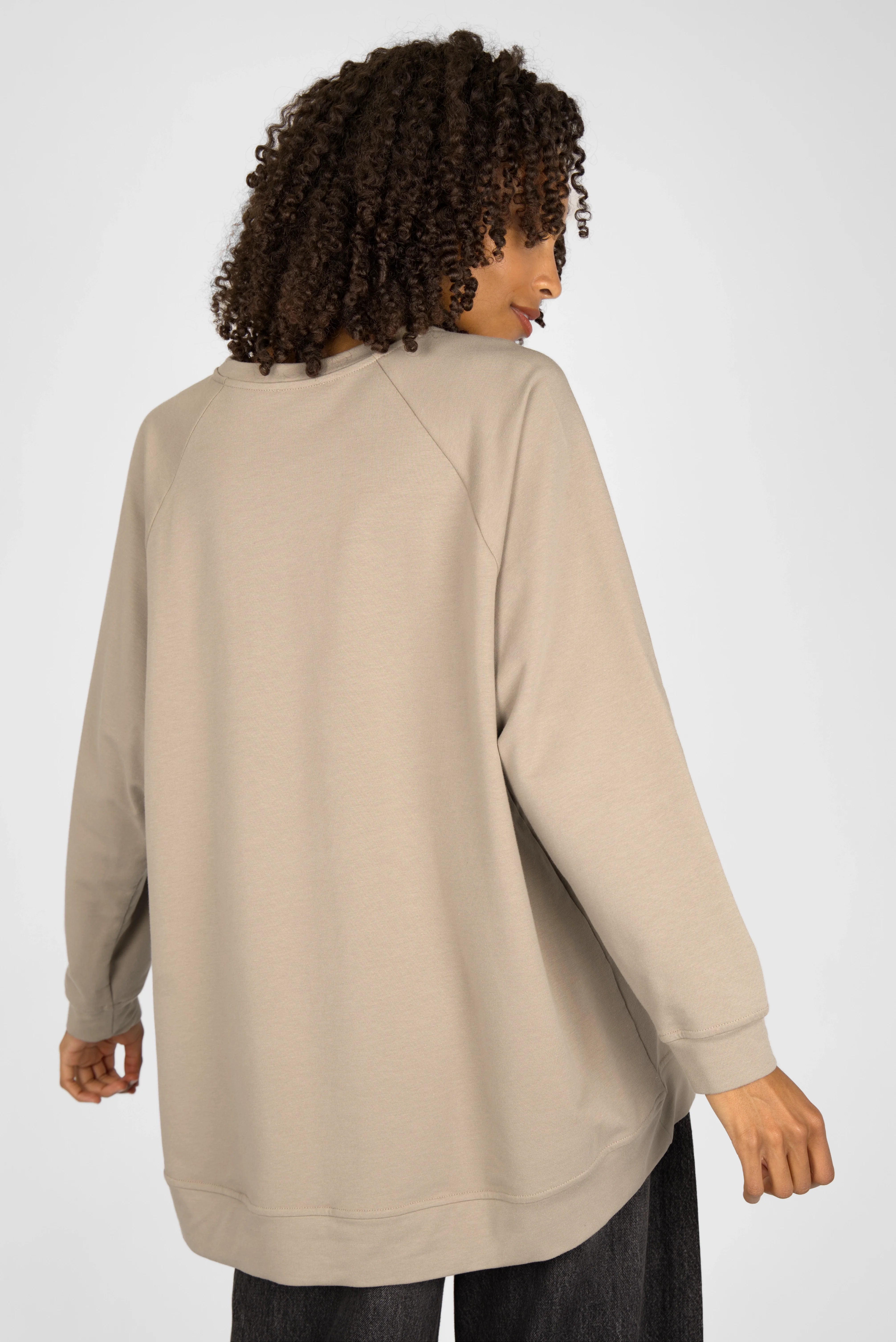 Back view of woman wearing beige GRACEY.K Sweater with oversized fit and longer back length