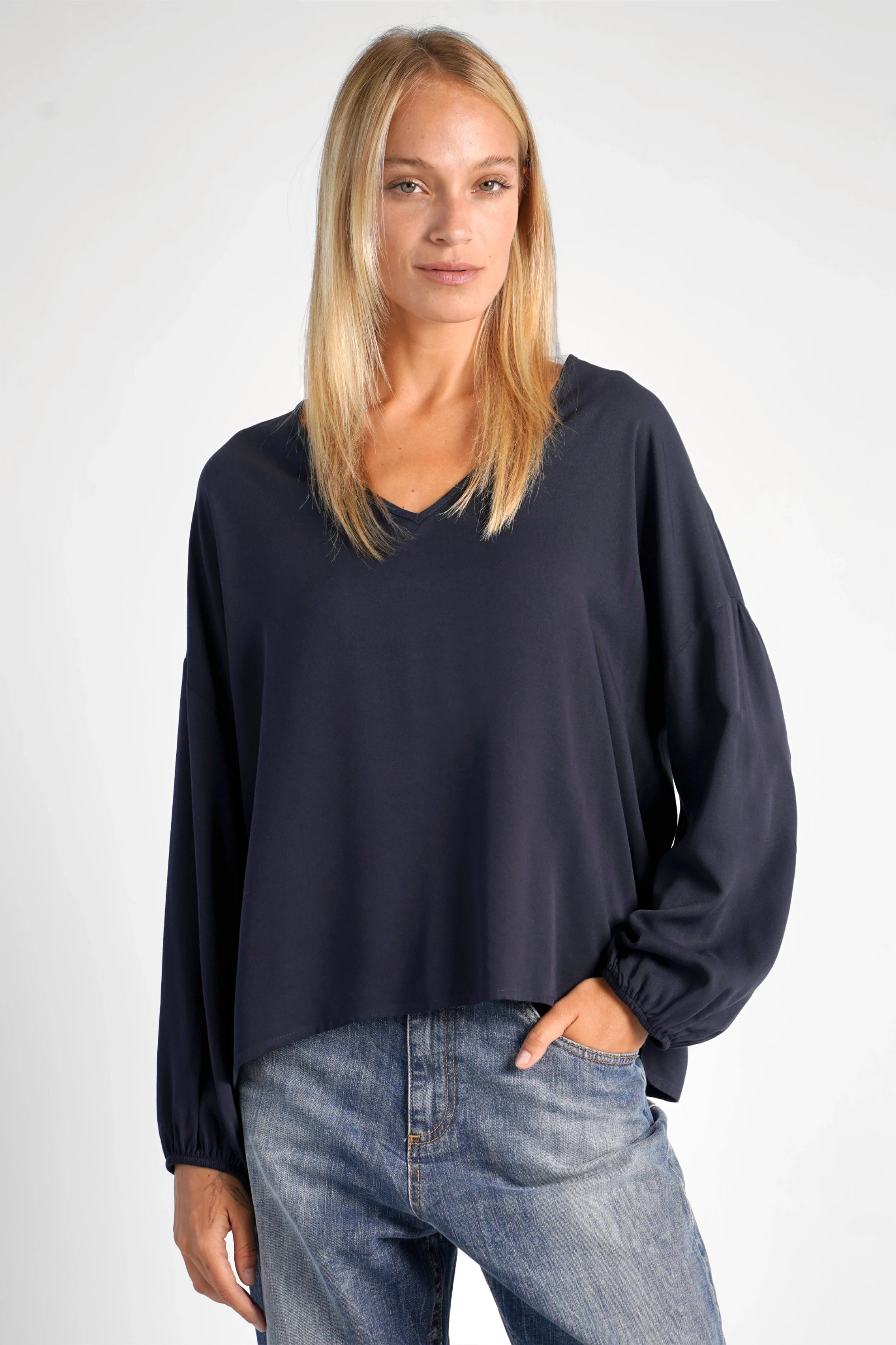 Frau trägt schwarze GRETA.K V-Neck Bluse aus leichter Viskose mit Ballonärmeln und lockerem Schnitt
