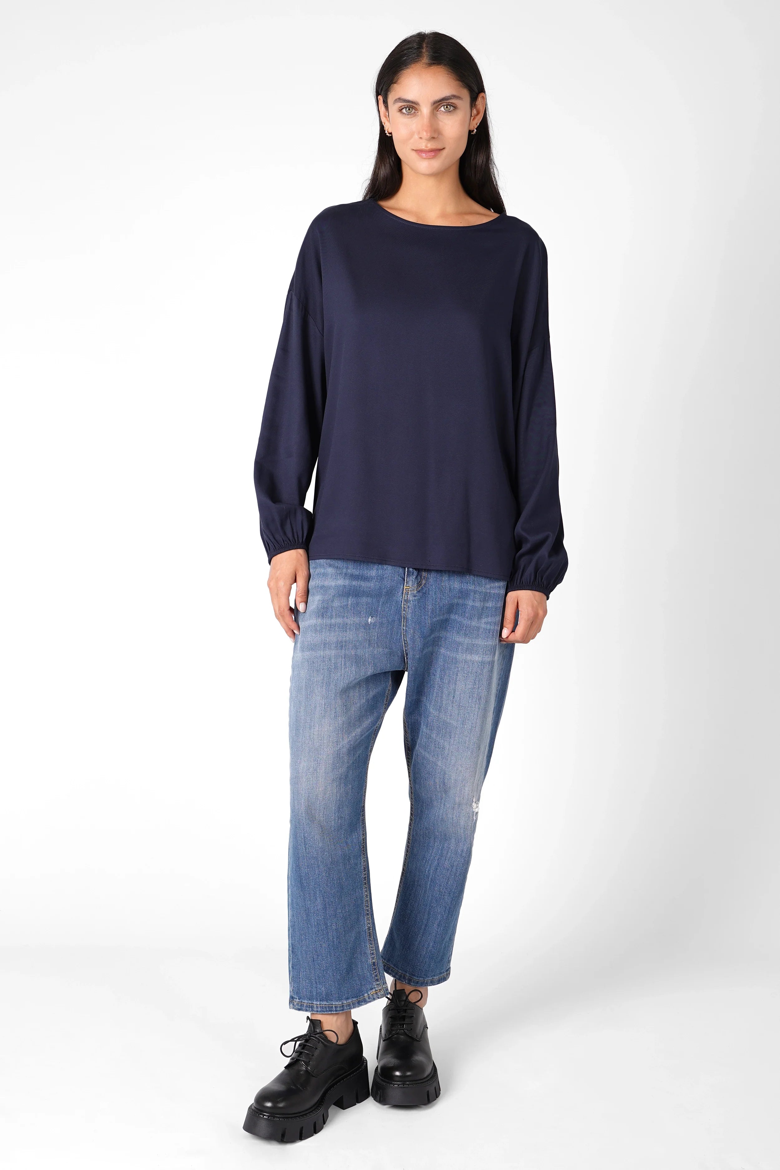 Dunkelblaue GRETA.K Bluse mit Rundhals und leichten Ballonärmeln aus seidiger Viskose, kombiniert mit Jeans und schwarzen Schuhen.