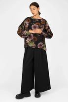 Woman wearing GRETA.K Bluse loose-fitting floral print blouse with round neck and balloon sleeves paired with wide-leg black pants
