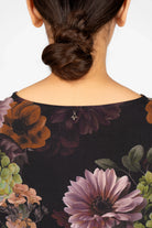 Back view of GRETA.K Bluse with dark floral allover print and round neckline on model with bun hairstyle.