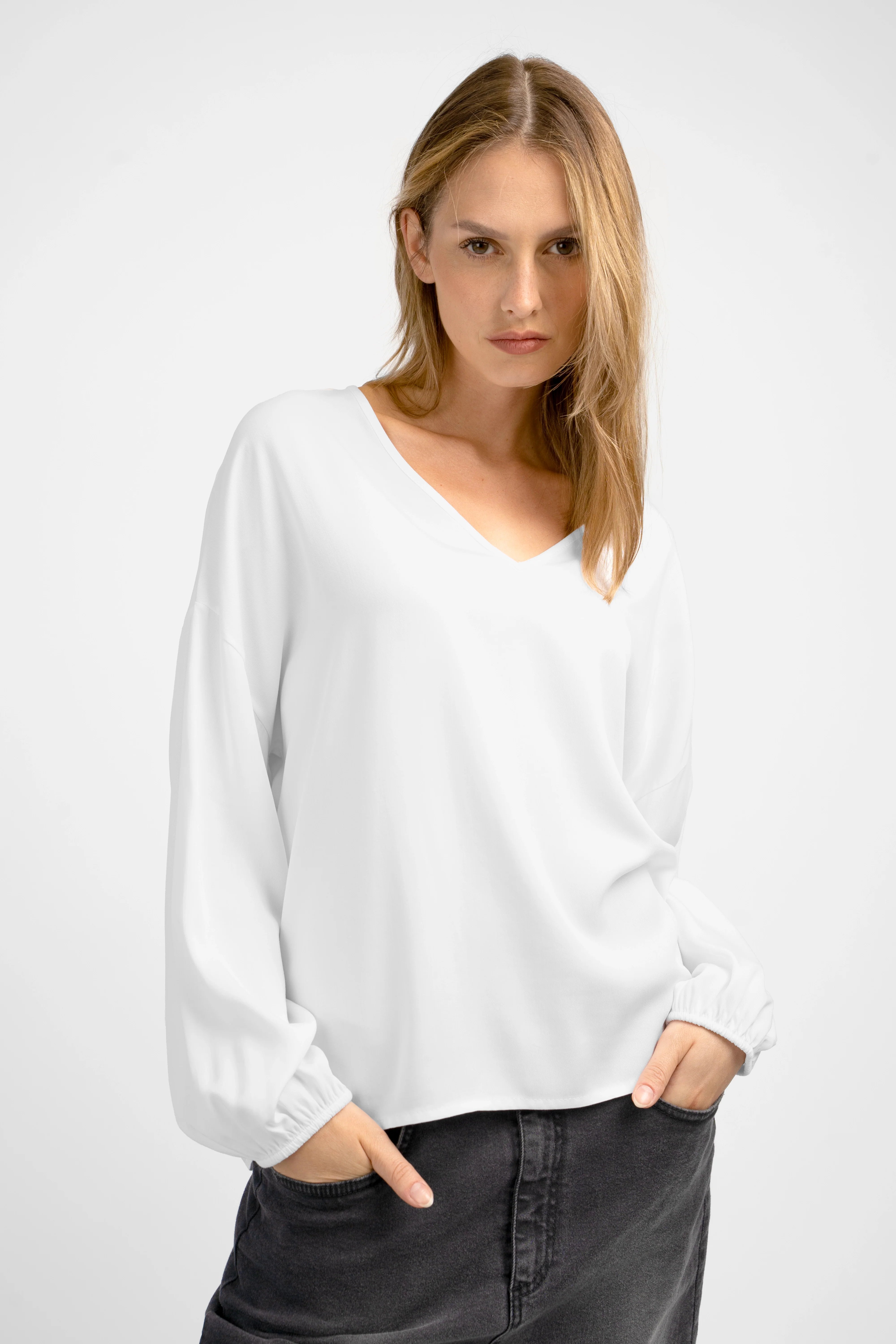 Damen trägt weiße GRETA.K V-Neck Bluse aus leichter Viskose mit Ballonärmeln und V-Ausschnitt