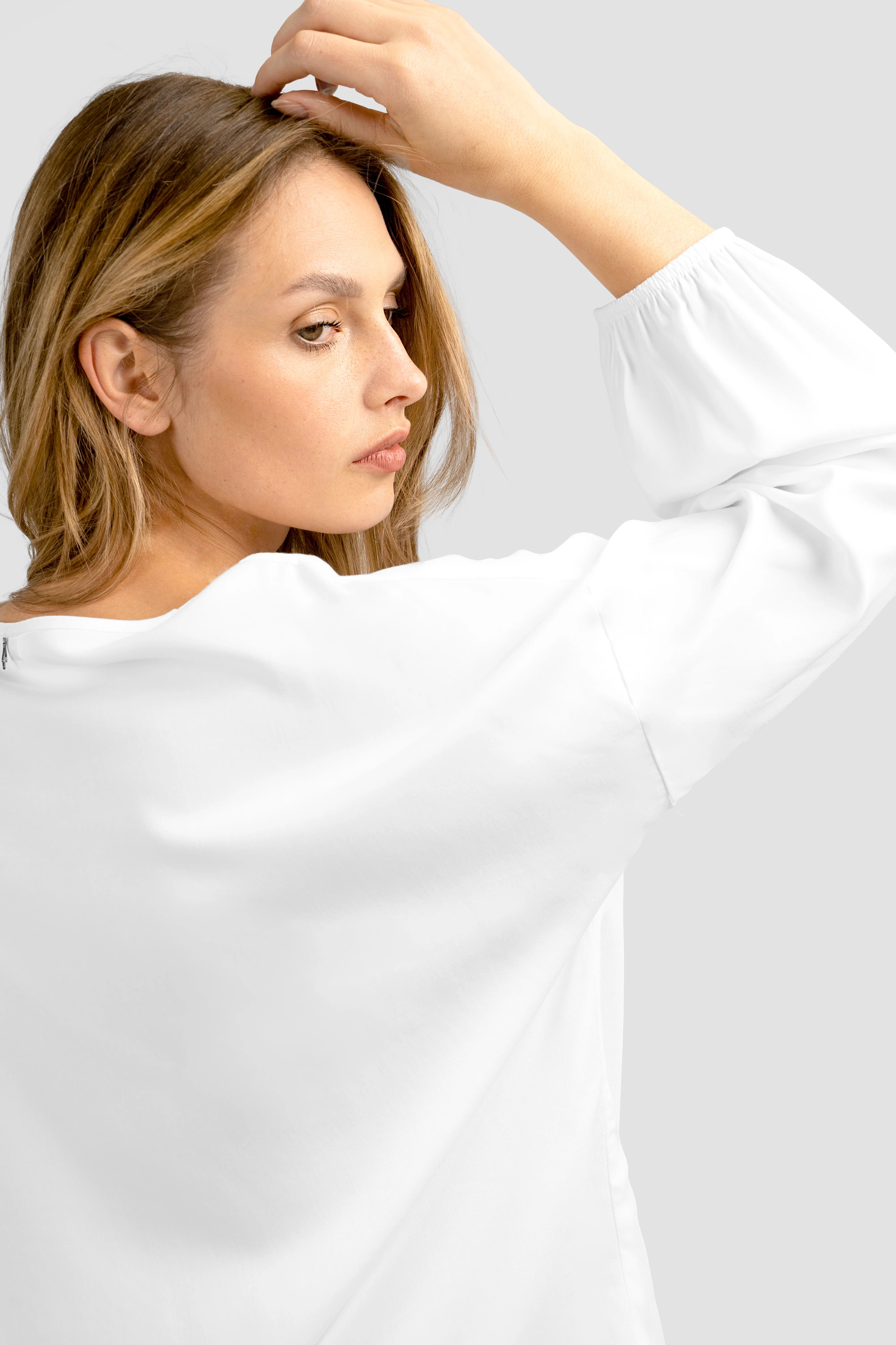 Damen trägt weiße GRETA.K V-Neck Bluse aus leichter Viskose mit V-Ausschnitt und Ballonärmeln