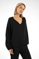 Frau trägt schwarze GRETA.K V-Neck Bluse aus leichter Viskose mit Ballonärmeln und V-Ausschnitt