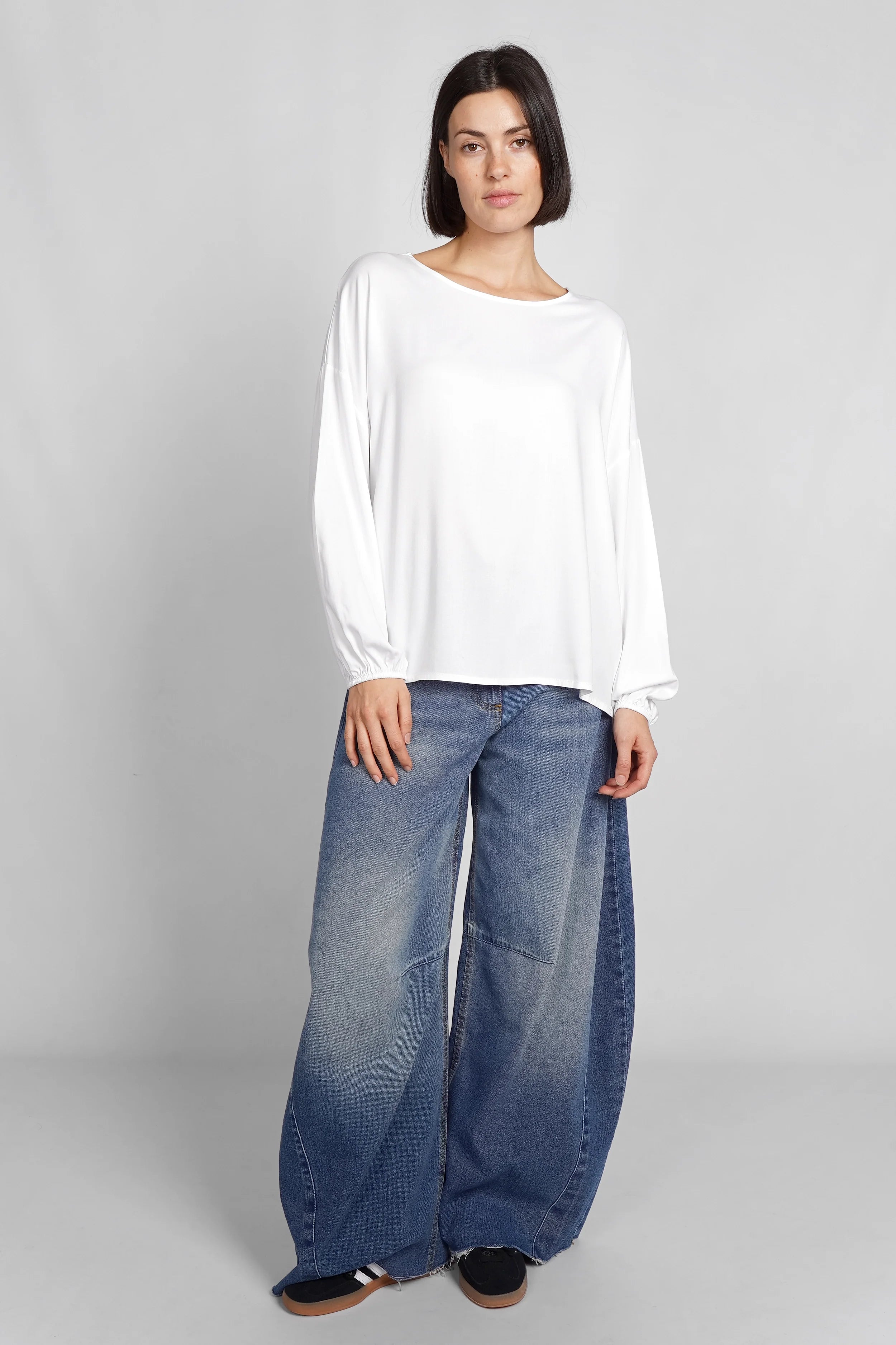 Frau trägt weiße locker geschnittene GRETA.K Bluse mit Rundhalsausschnitt und langen Ärmeln aus weicher Twill Viskose