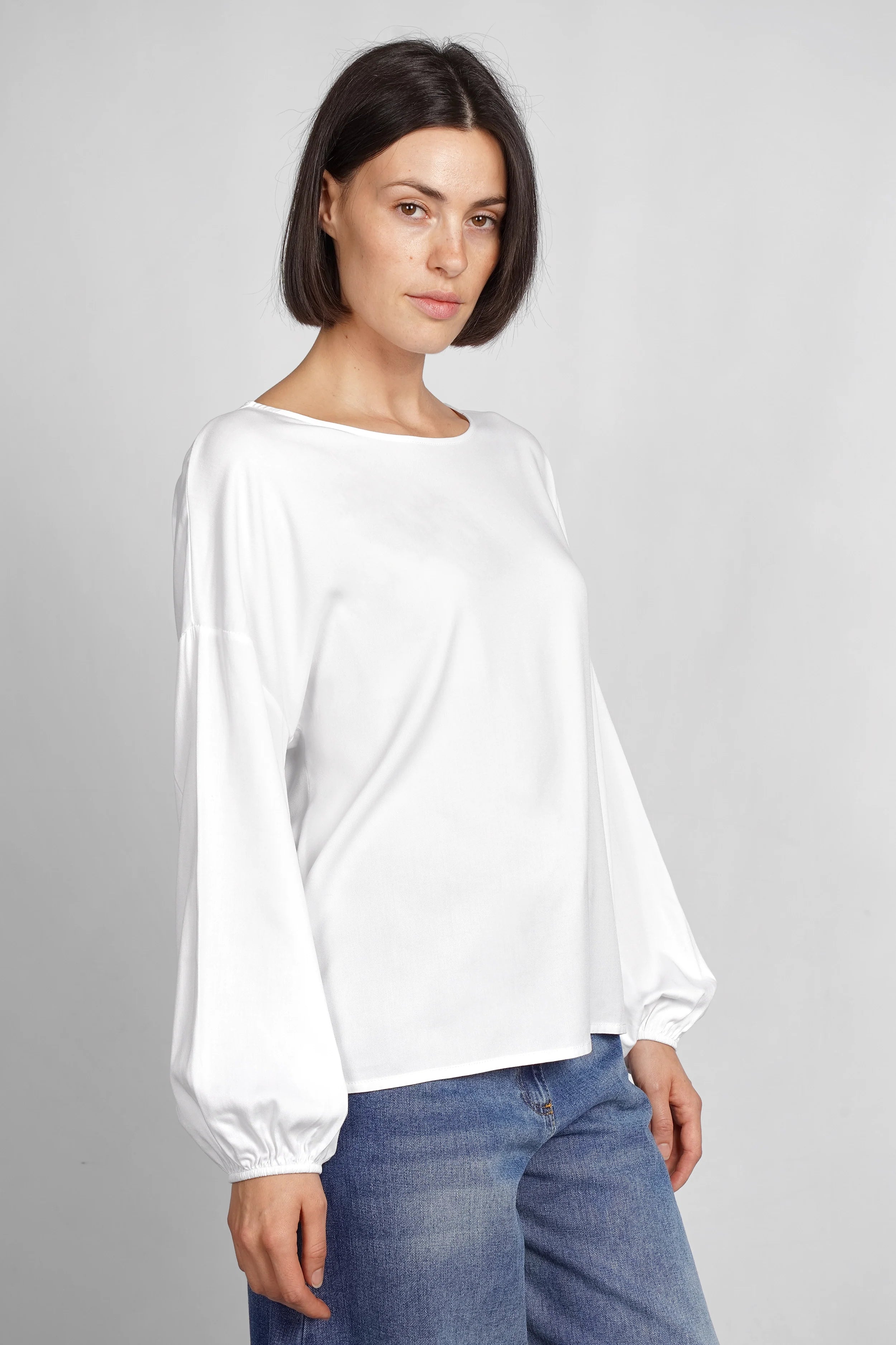 Frau trägt weiße locker geschnittene GRETA.K Bluse mit Rundhals, überschnittenen Schultern und langen Ärmeln aus Twill Viskose