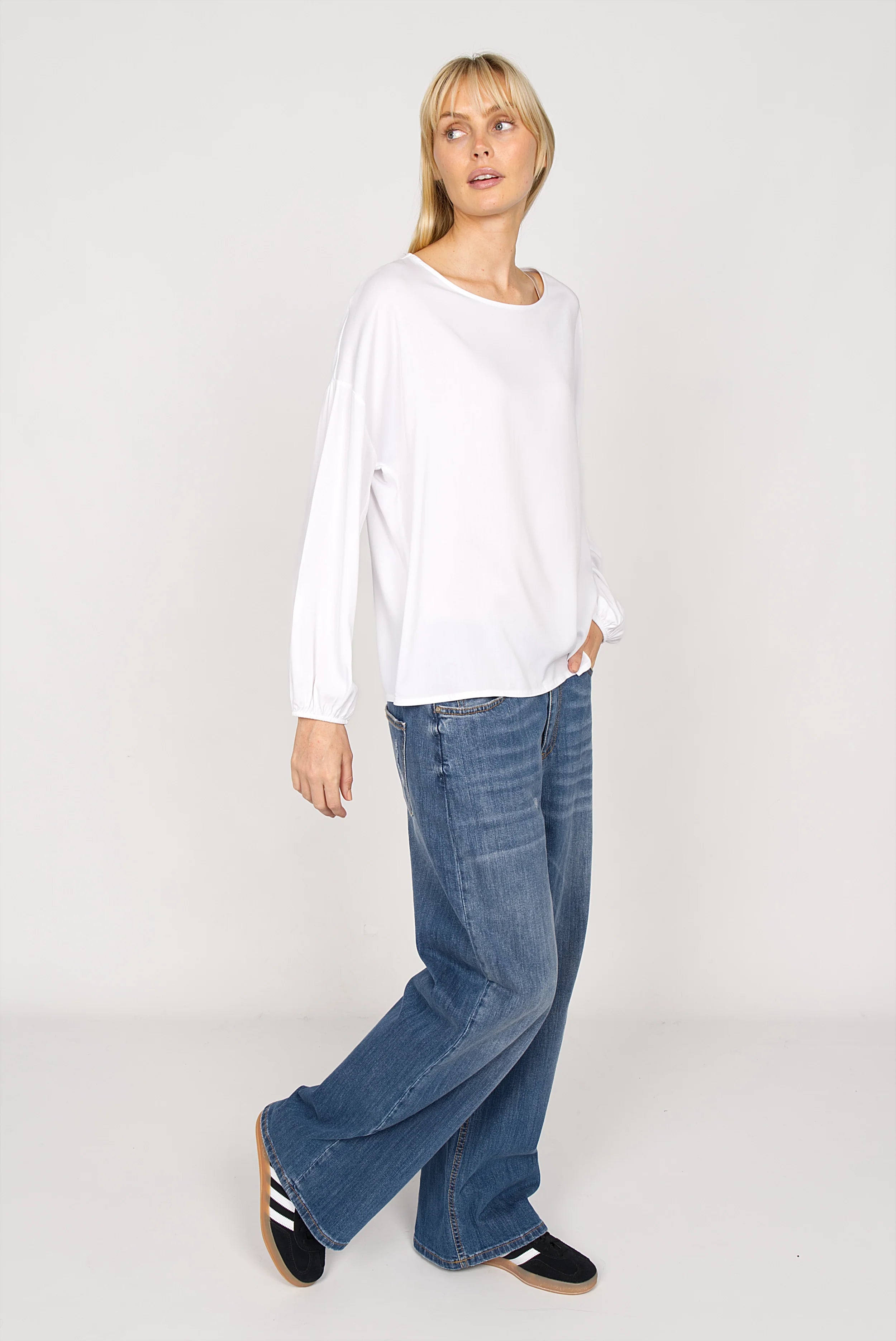 Damen trägt locker geschnittene weiße GRETA.K Bluse mit Rundhalsausschnitt und langen Ärmeln aus Twill Viskose