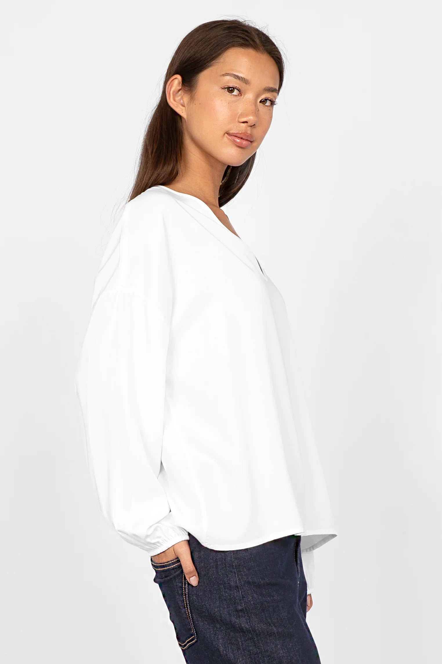 Frau trägt locker geschnittene weiße GRETA.K V-Neck Bluse aus weicher Twill Viskose mit V-Ausschnitt und elastischen Ärmelabschlüssen