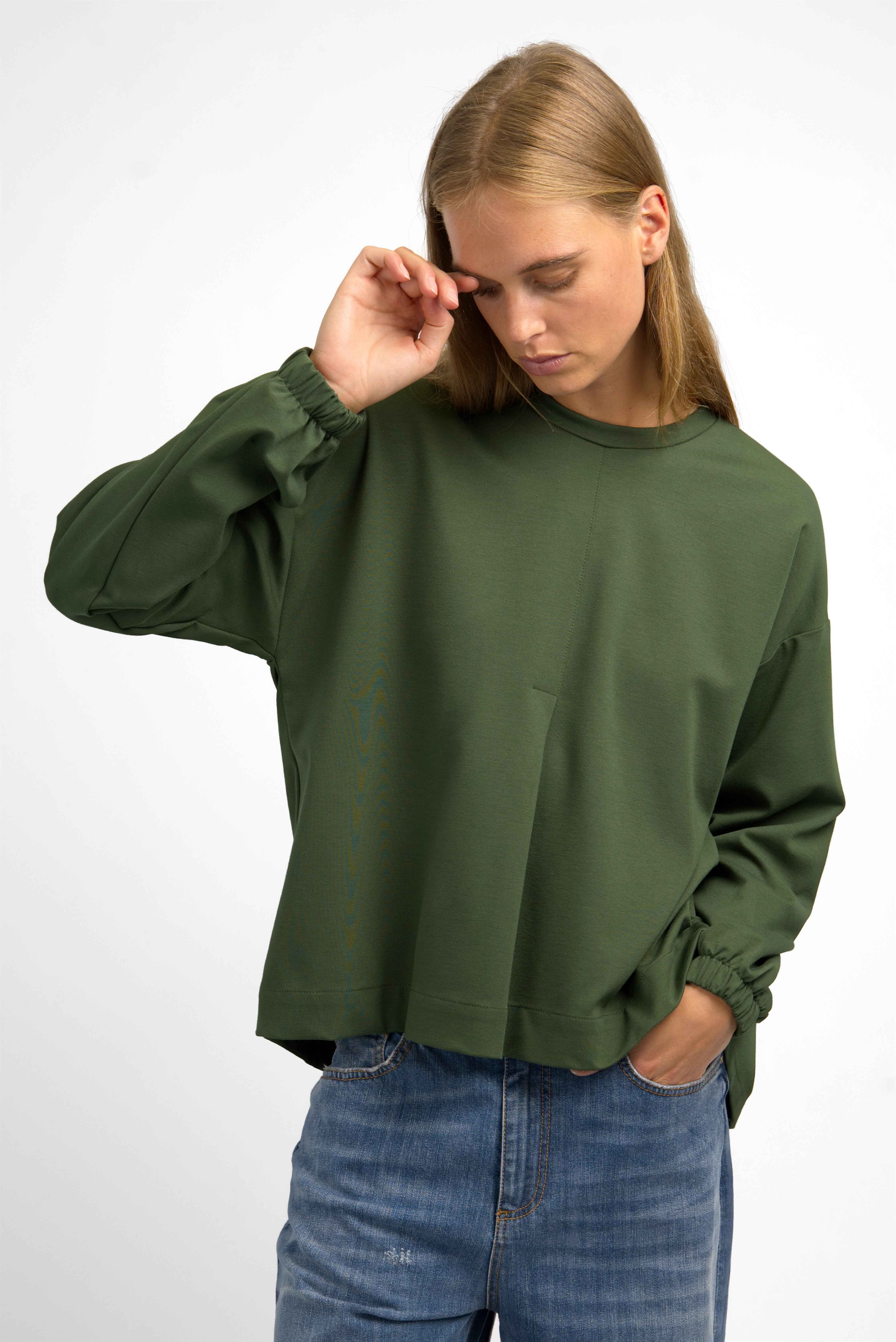 Woman wearing olive green HAGLA Shirt with relaxed fit, round neckline, elastic cuffs, and subtle front pleat