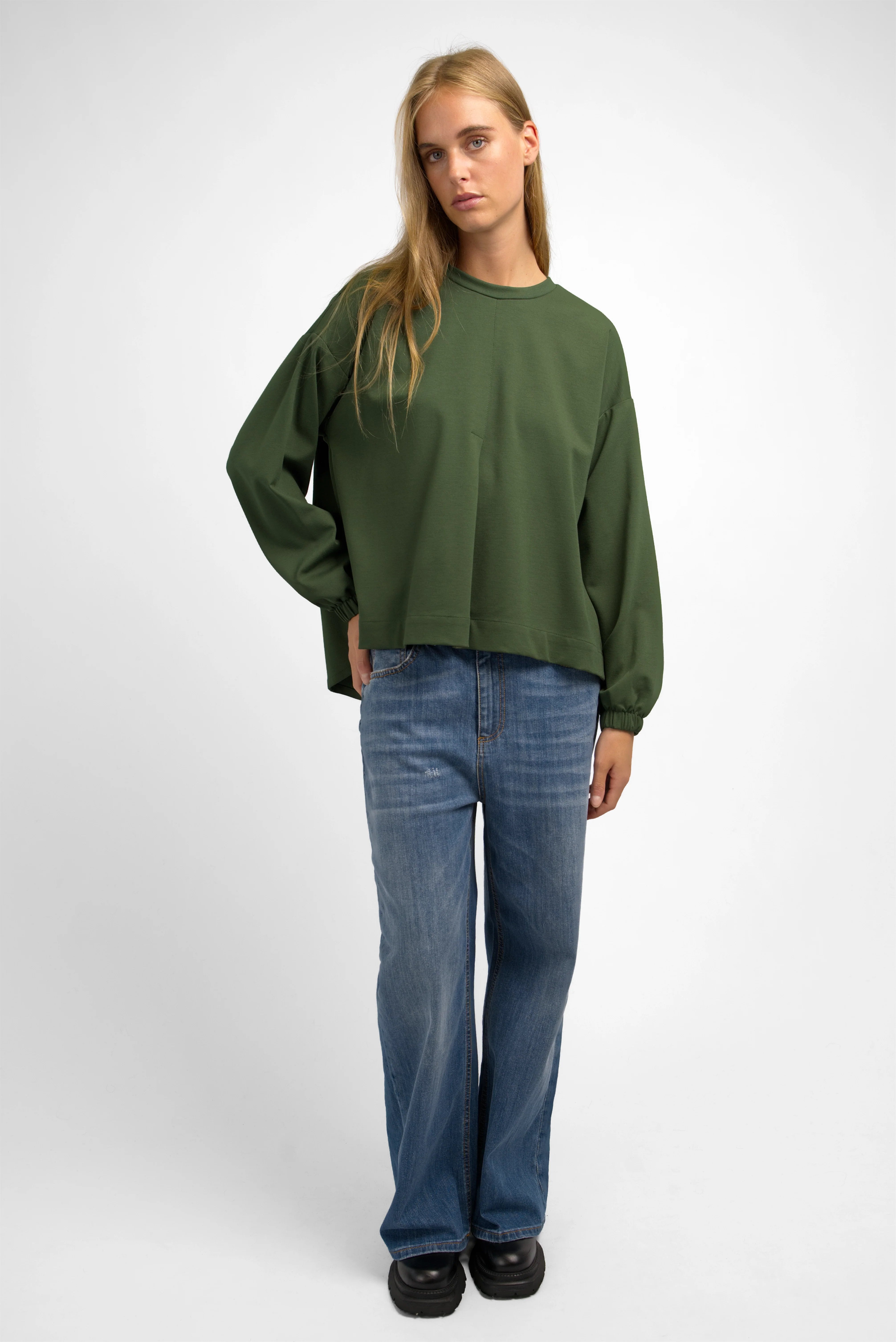 Relaxed fit HAGLA Shirt in olive green with round neckline, elastic cuffs, and subtle back pleat, worn with blue jeans.