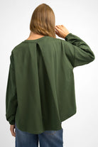 Woman wearing olive green HAGLA Shirt with relaxed fit, elastic cuffs, and back pleat detail.