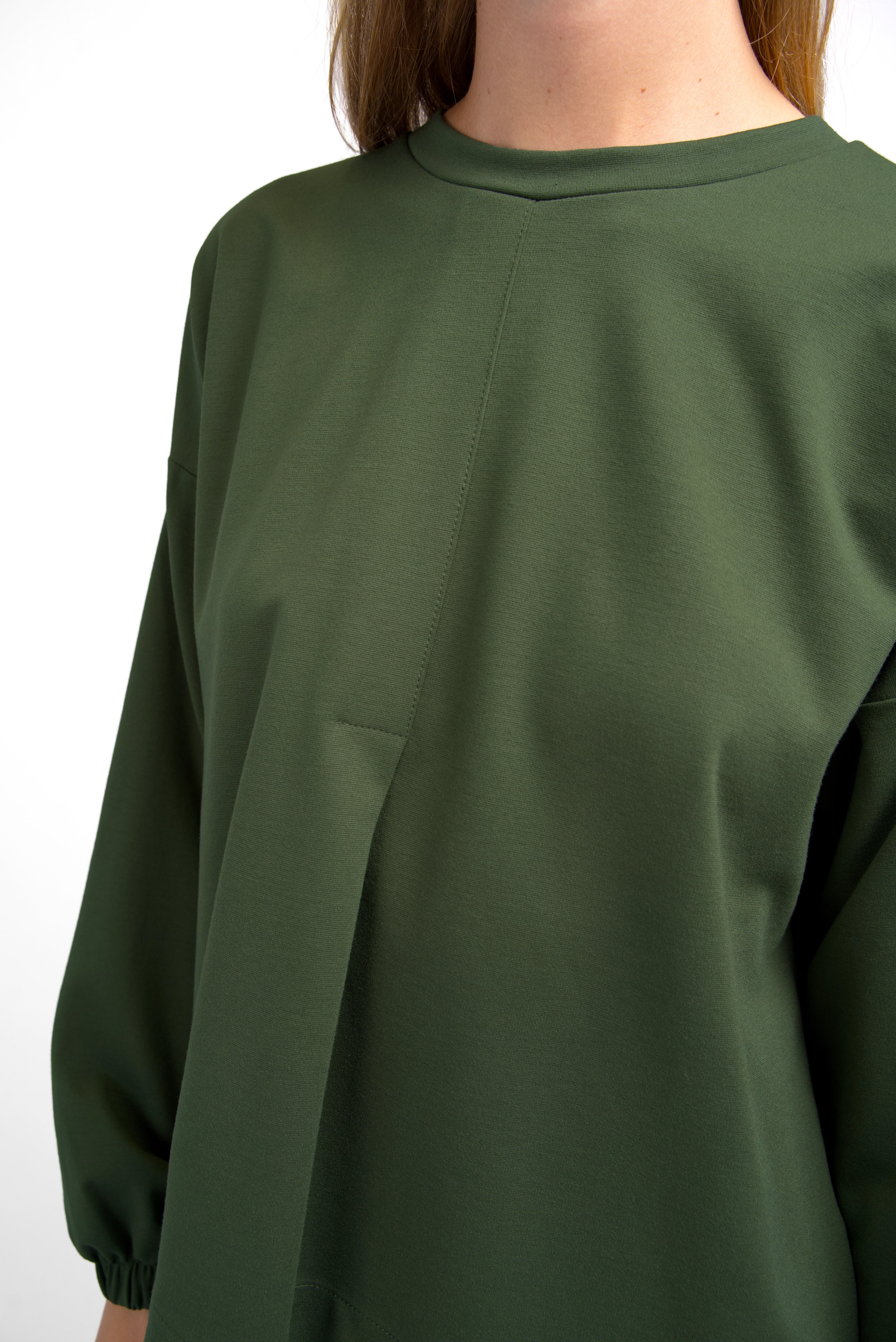 HAGLA Shirt in olive green with round neckline, elastic cuffs, front decorative pleat, and relaxed fit.