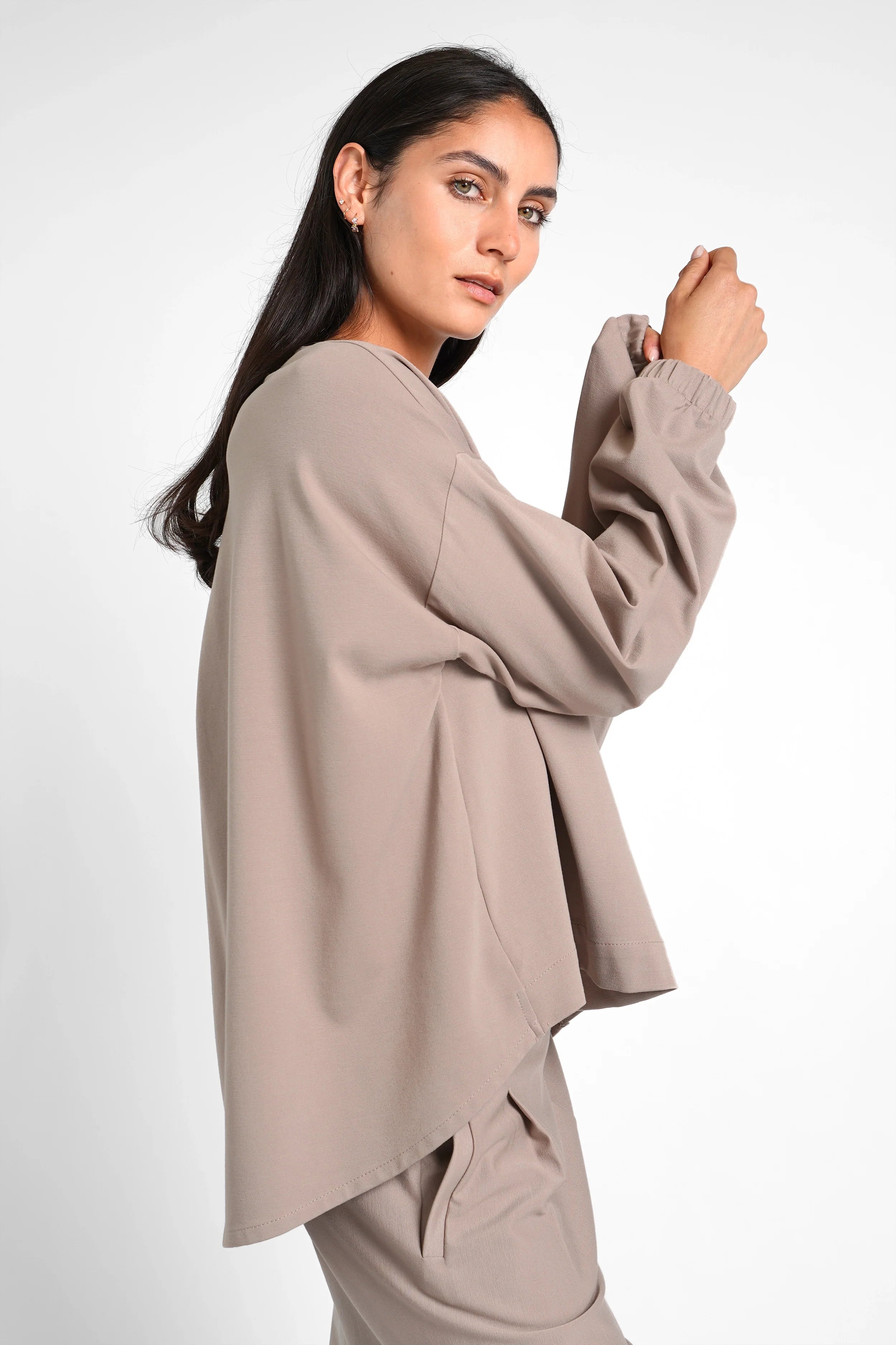 Woman wearing taupe HAGLA Shirt with relaxed fit, round neckline, elastic cuffs, and longer back hem.