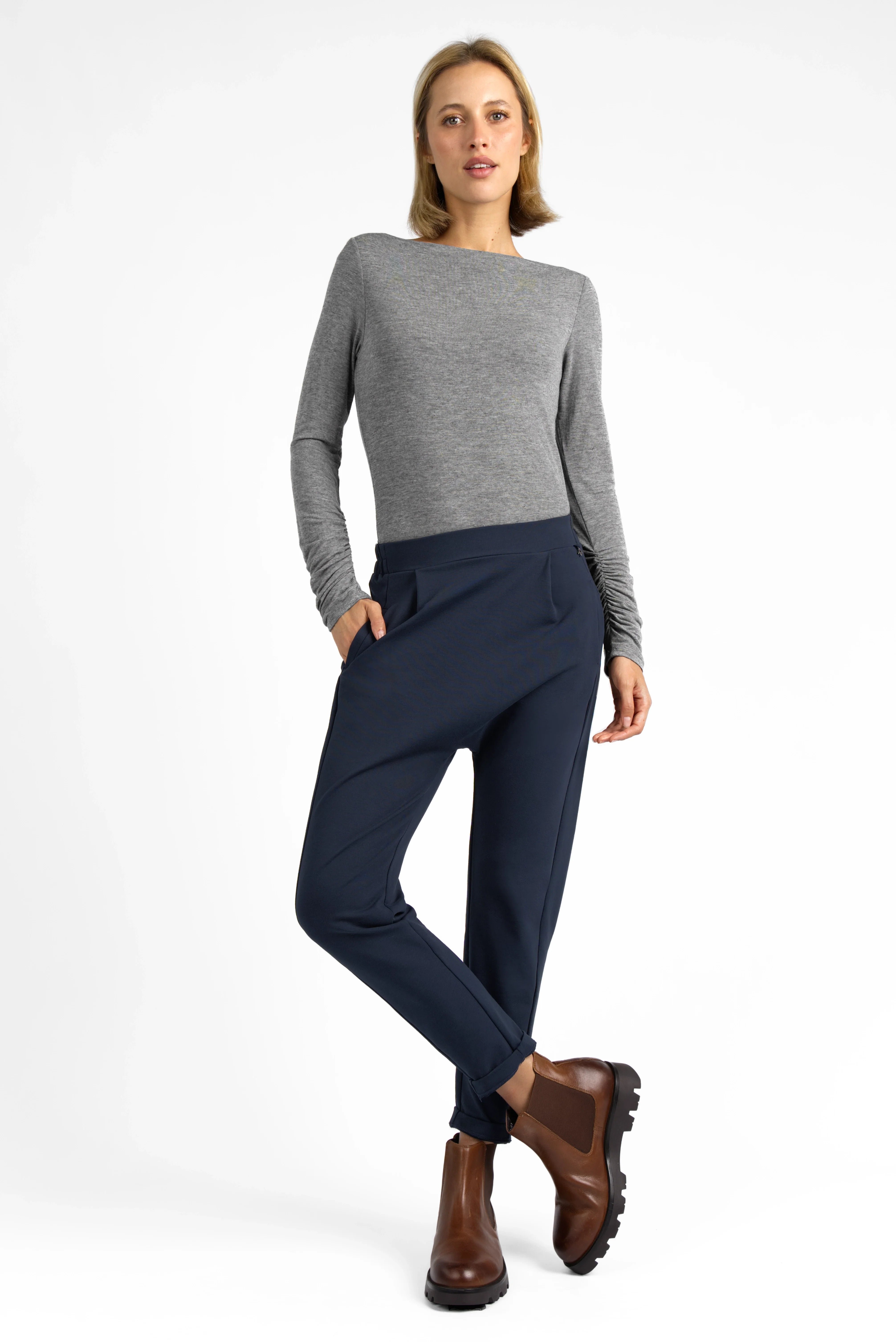 Damen trägt HANNA.K Tapered Sweathose in Navy mit elastischem Bund und Taschen, kombiniert mit grau meliertem Langarmshirt und braunen Stiefeln