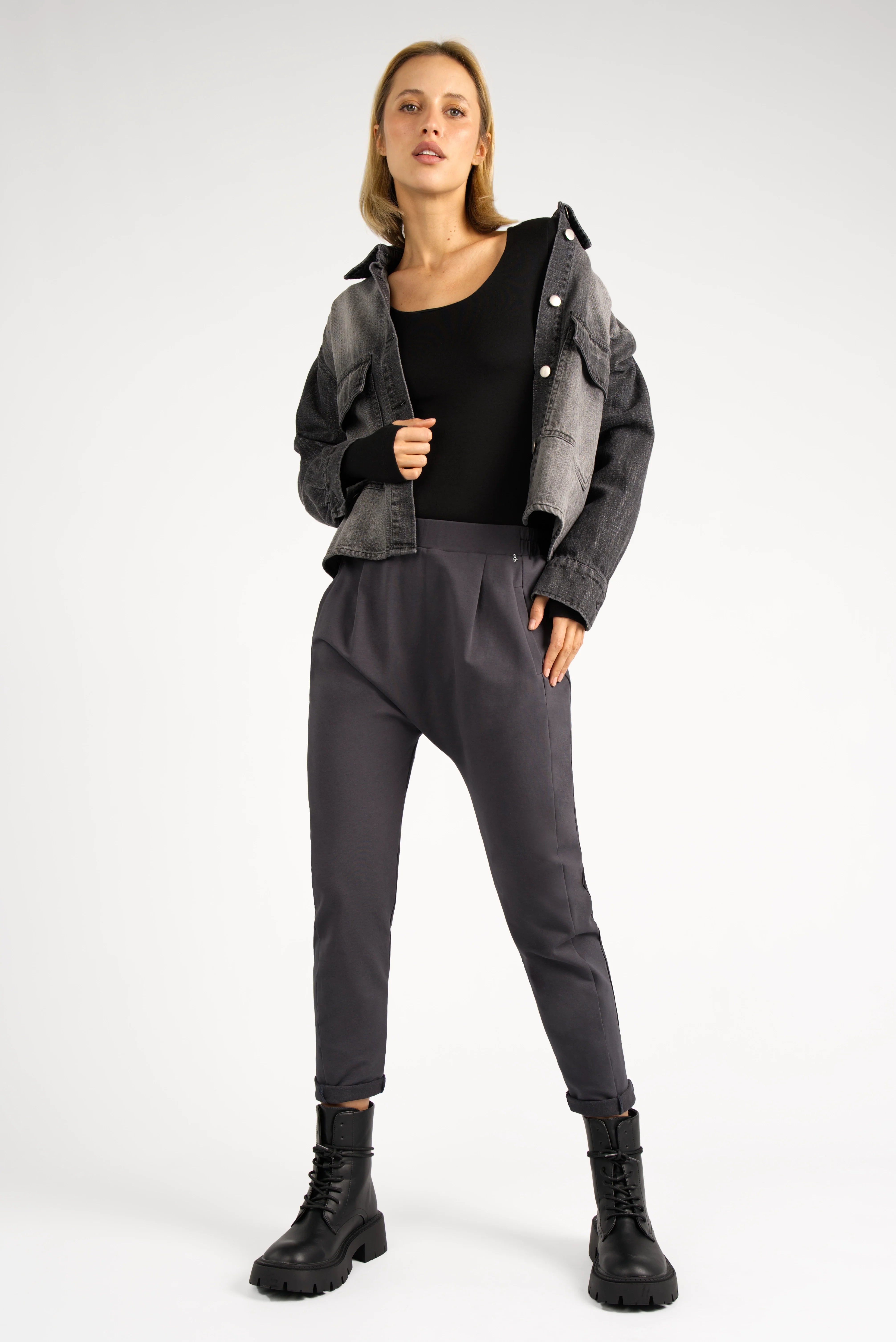 Damen in schwarzer HANNA.K Tapered Sweathose mit elastischem Bund, tiefem Schritt und schmal zulaufendem Bein, kombiniert mit schwarzem Top und grauer Jacke.