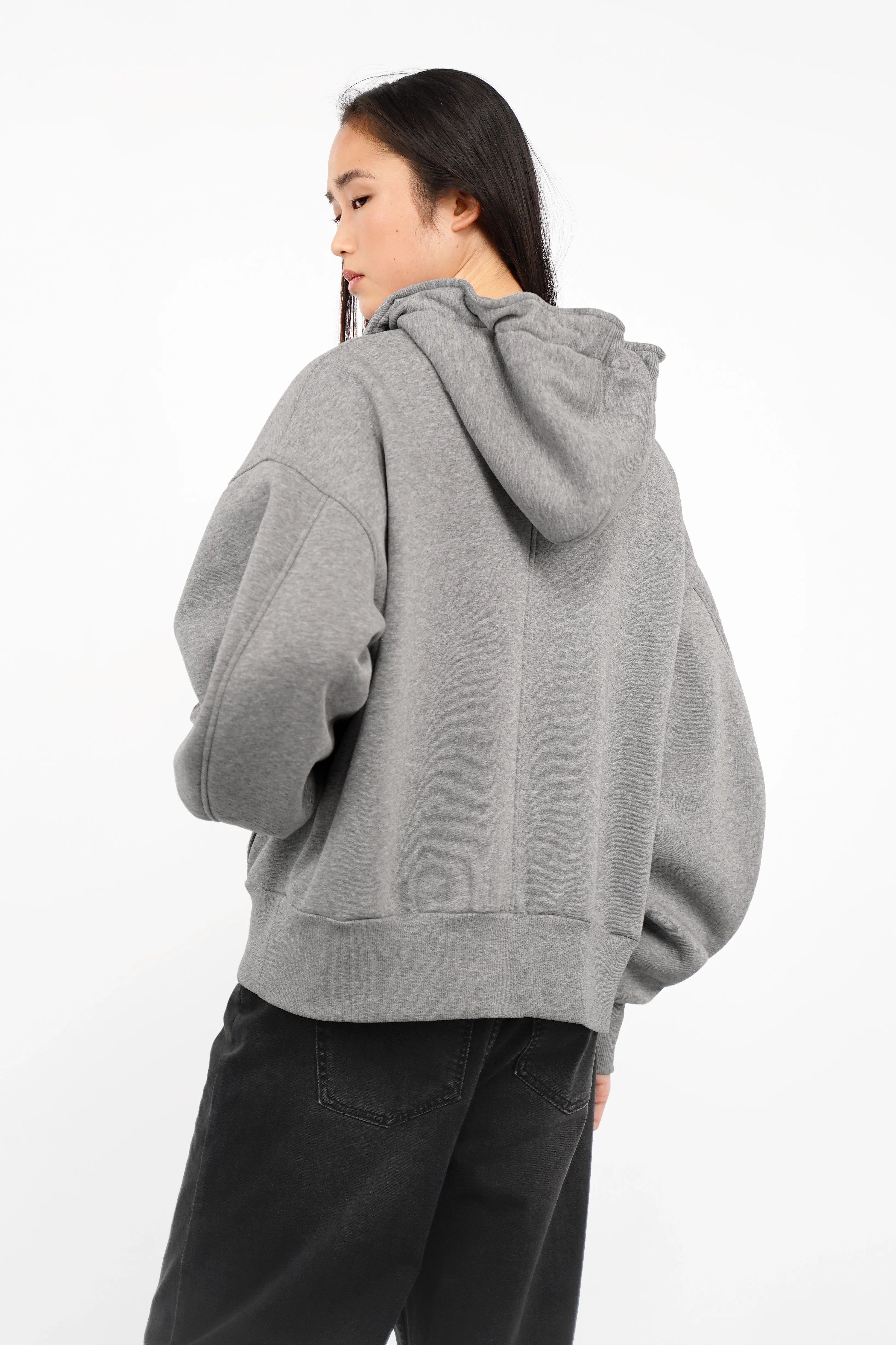 Gray relaxed fit zip-hoodie with oversized sleeves and hood worn by a woman from the back