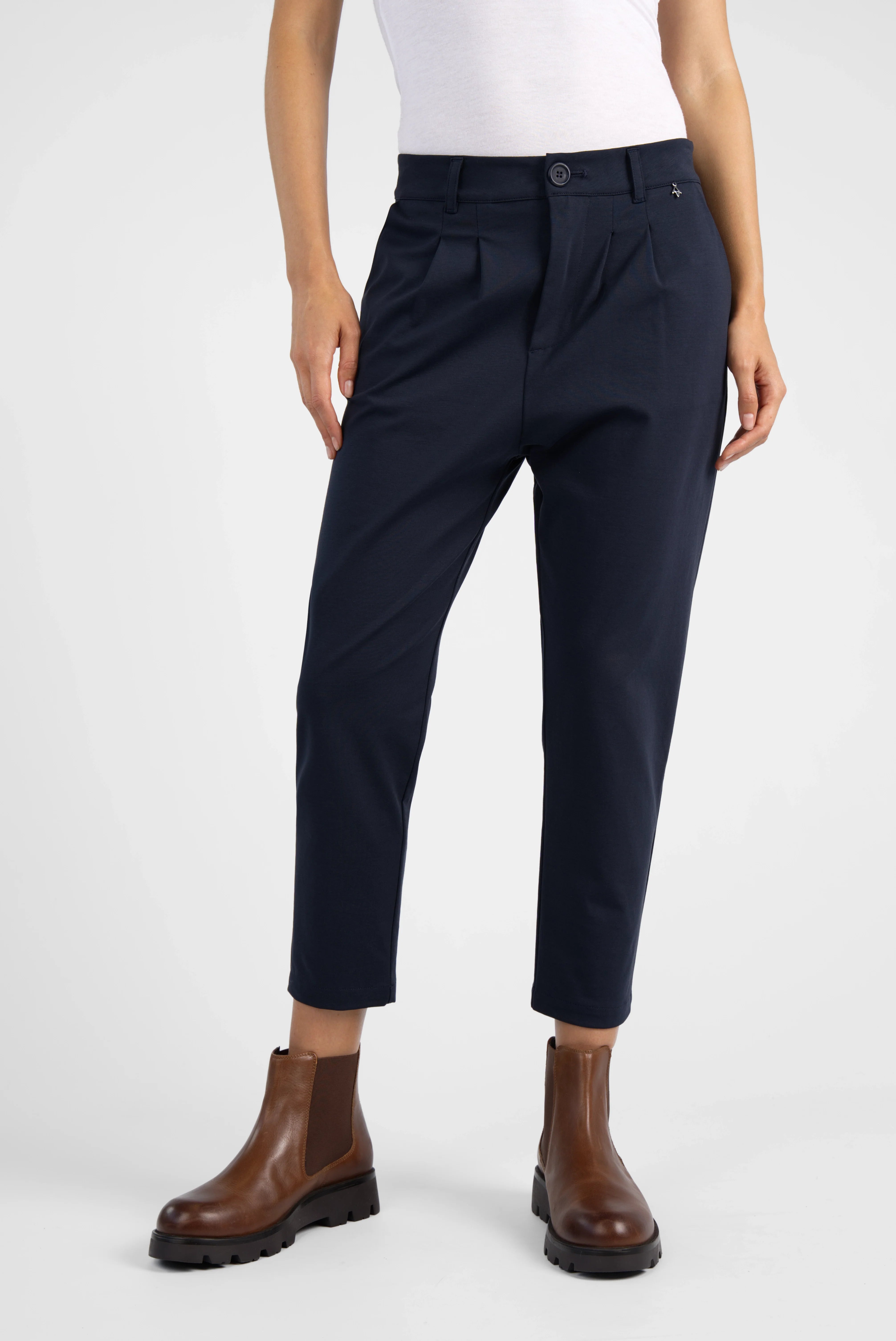Dunkelblaue HEELENA OG Tapered Pants mit normaler Bundhöhe, Cropped Länge und schmal zulaufendem Bein, kombiniert mit braunen Stiefeln.
