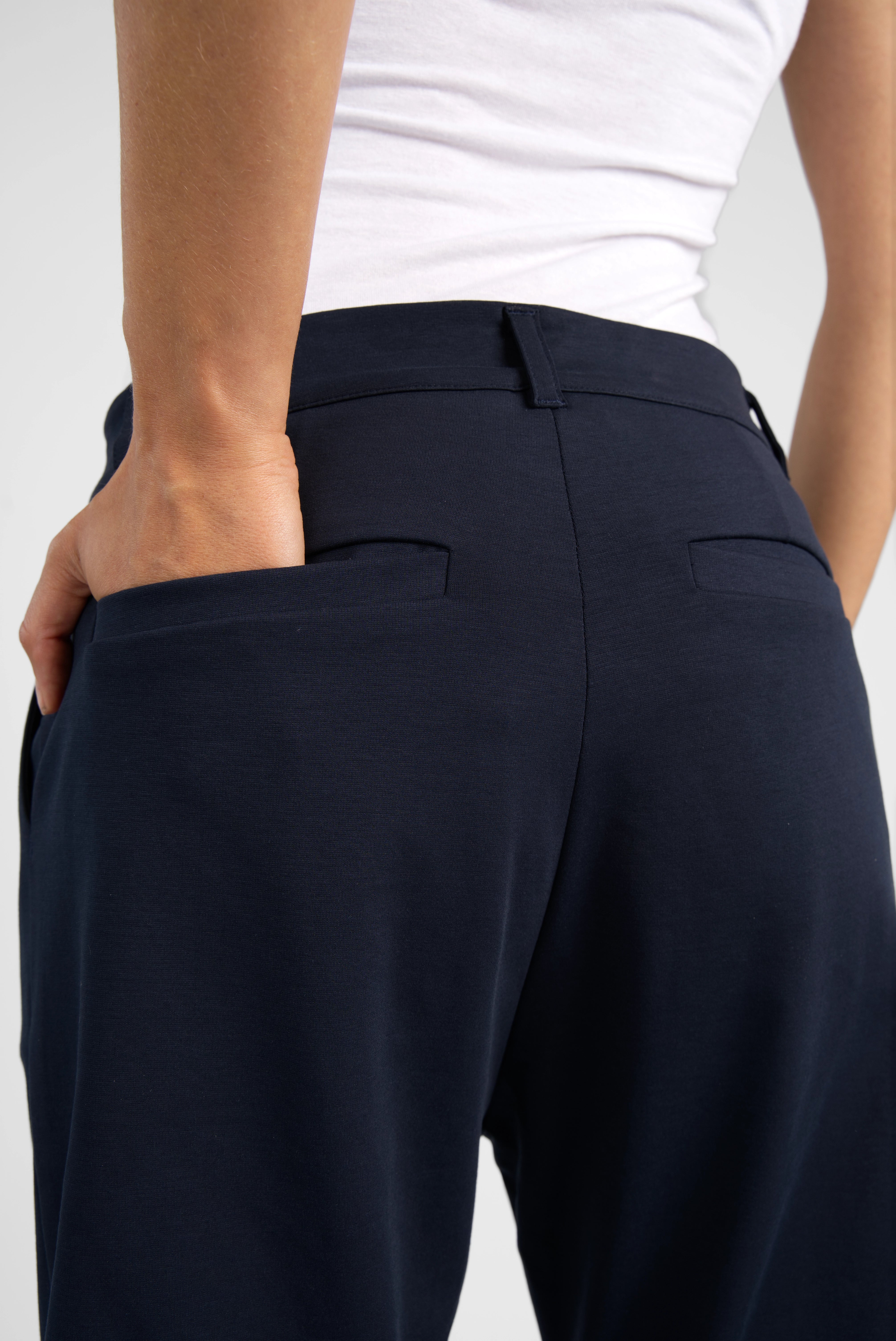 Dunkelblaue HEELENA OG Tapered Pants cropped mit schmal zulaufendem Bein und weichem Stoff, getragen von Model von hinten.