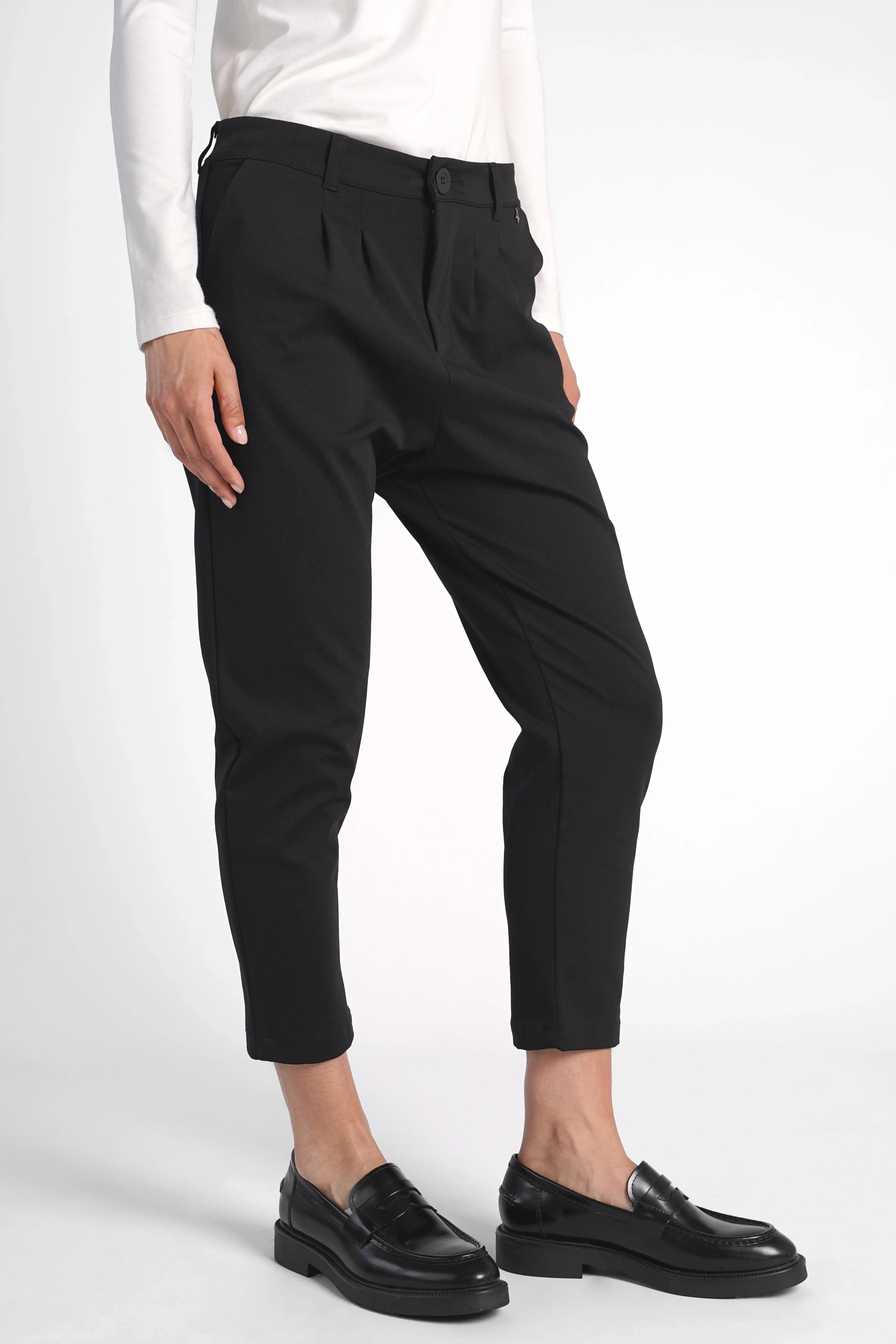Schwarze HEELENA OG Tapered Pants cropped mit normaler Bundhöhe und schmal zulaufendem Bein, kombiniert mit schwarzen Loafers.