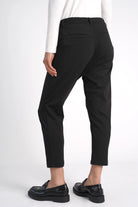 Schwarze HEELENA OG Tapered Pants cropped mit schmal zulaufendem Bein und normaler Bundhöhe, getragen mit schwarzen Slippern.