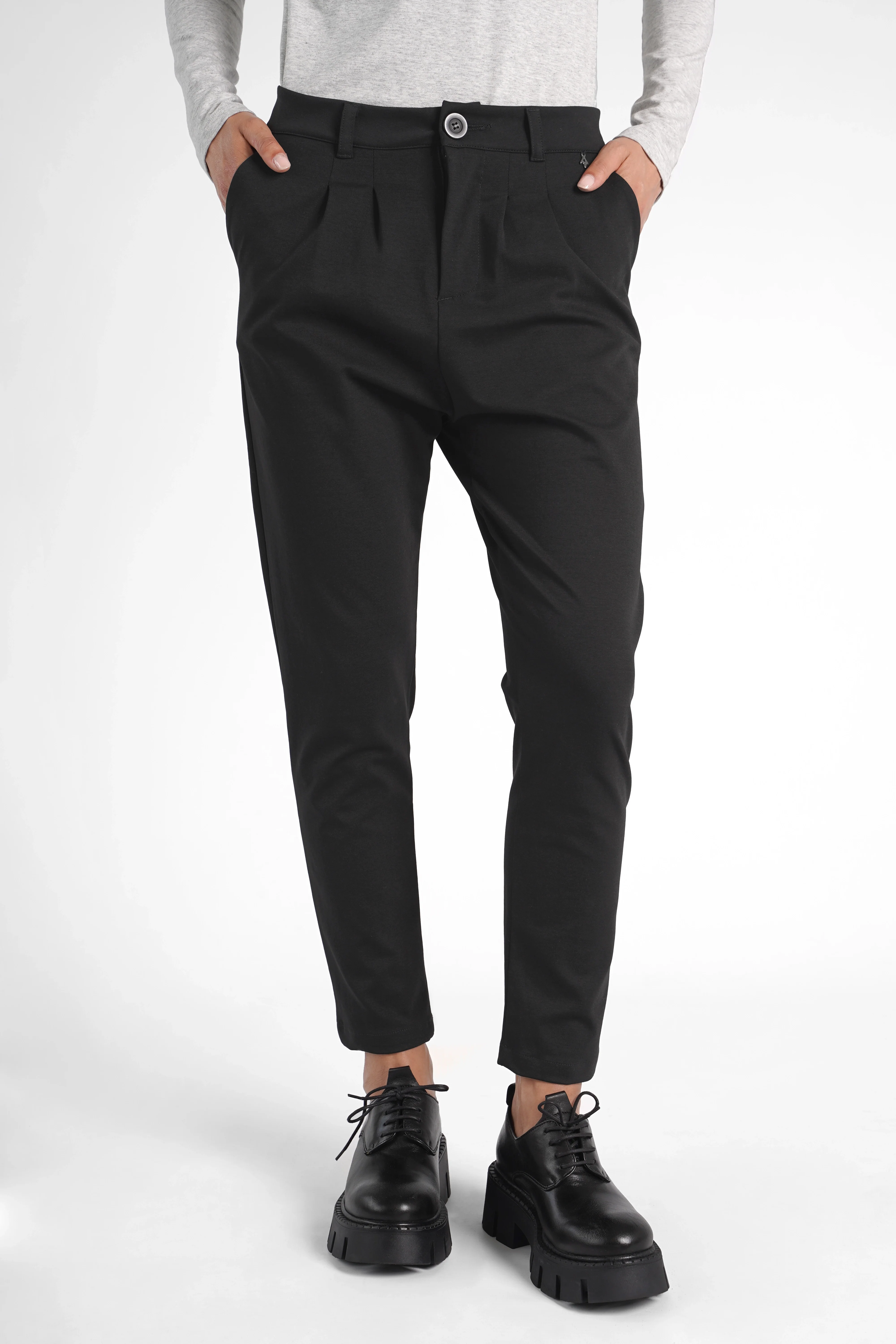 Schwarze HEELENA OG Tapered Pants mit schmal zulaufendem Bein und normaler Bundhöhe, getragen von Model mit weißen Oberteil und schwarzen Schuhen.