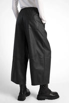 Black HERA Wide Leg Hose in soft eco-leather with elastic waistband and side pockets, styled with black boots.