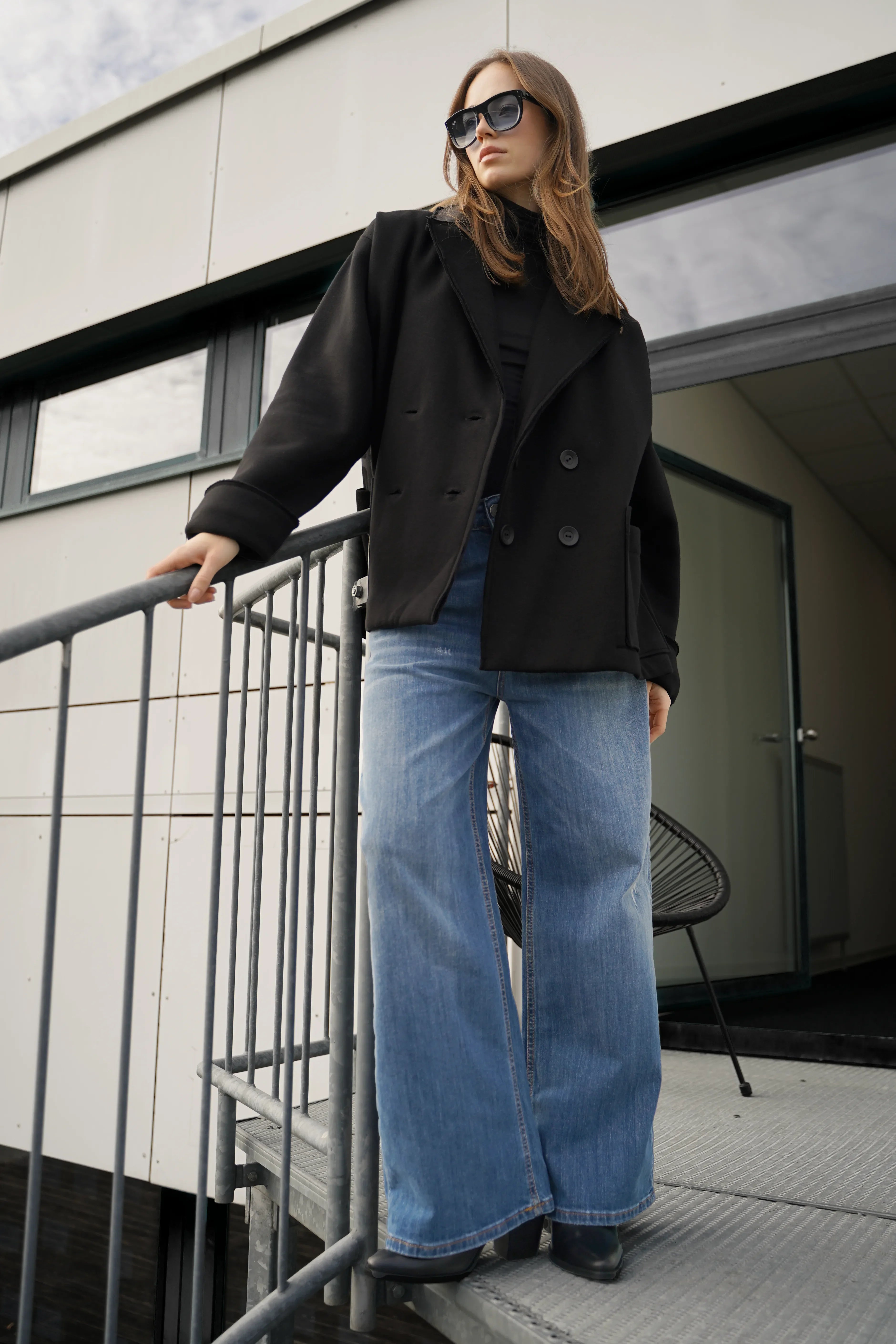 Frau trägt schwarzen HELIEE Oversized Sweat-Kurzmantel mit Reverskragen und Doppelknöpfen in urbaner Umgebung