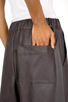 Close-up of HERA Wide Leg Hose in dark eco-leather with elastic waistband and back patch pocket detail.