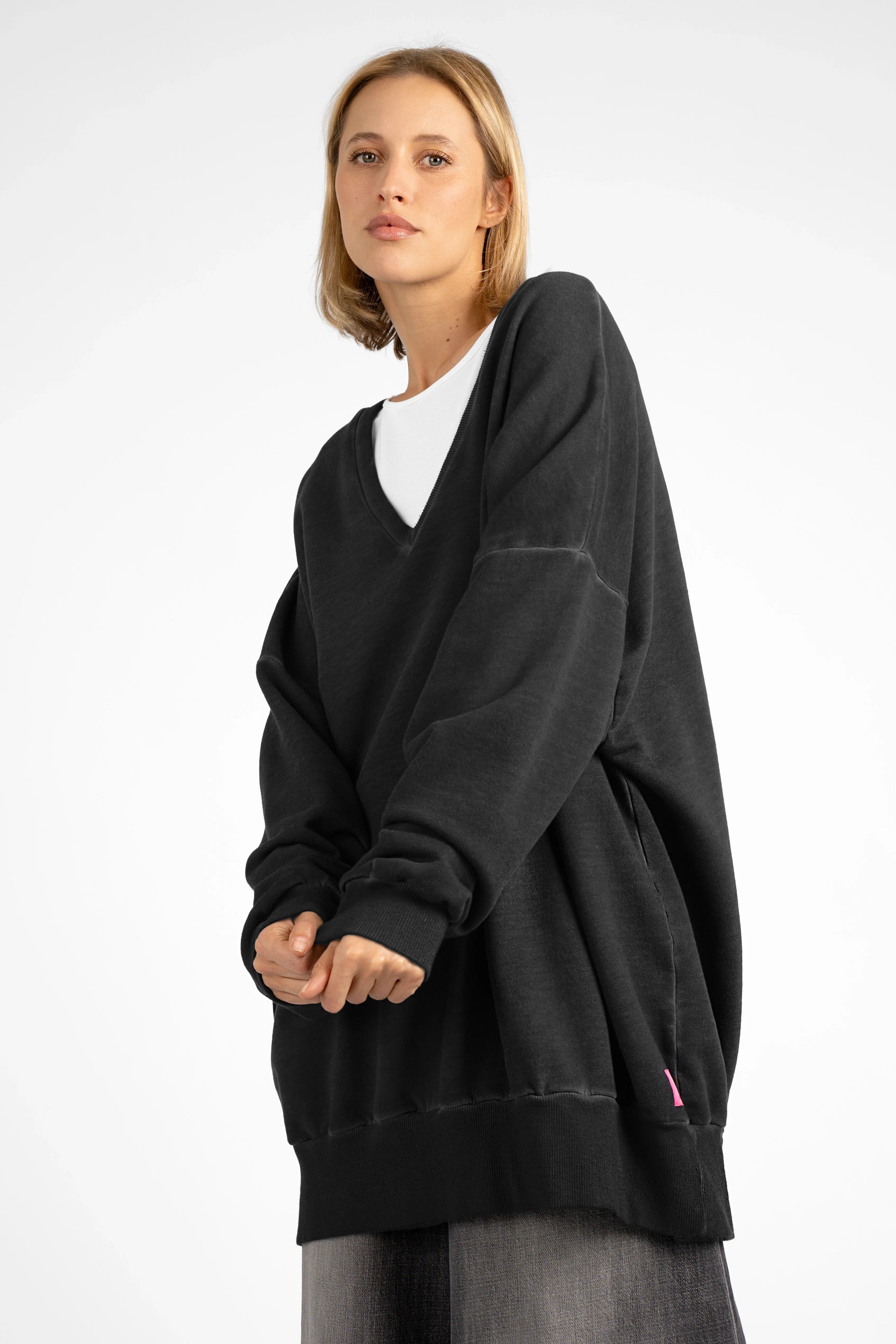 Woman wearing oversized black IMIKO Studio Long-Sweater with deep V-neck and dropped shoulders